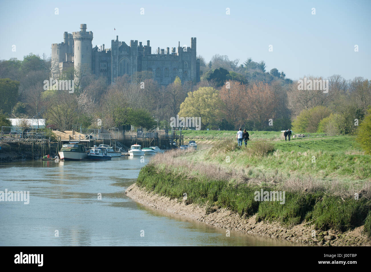 People walk along the bank of the River Arun in front of Arundel Castle