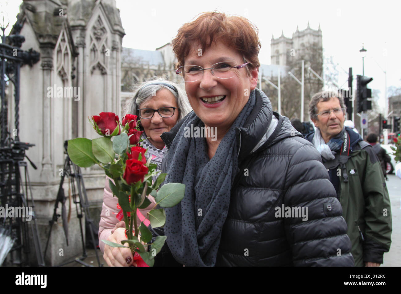 A group of men 'From Russia With Love Make Her Smile' hand out red roses to women outside Parliament to celebrate International Women's Day 2017 in London  Featuring: Atmosphere Where: London, United Kingdom When: 08 Mar 2017 Stock Photo