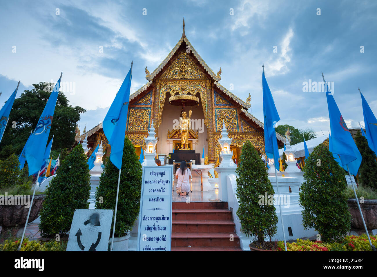 Chiang Mai, Thailand - August 21, 2016: Woman pray at the Wat Phra Singh temple decorated with Queens Blue Flags on August 21, 2016 in Chinag Mai, Tha Stock Photo
