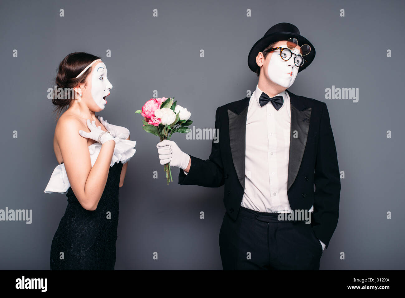 Pantomime actor and actress performing with flower bouquet. Mime theater performers posing