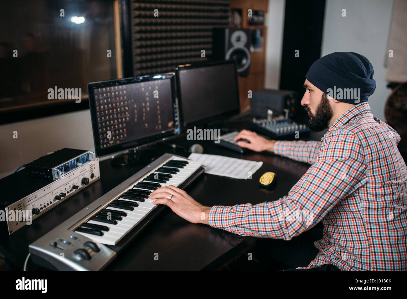 Audio engineer work with musical keyboard in studio. Professional