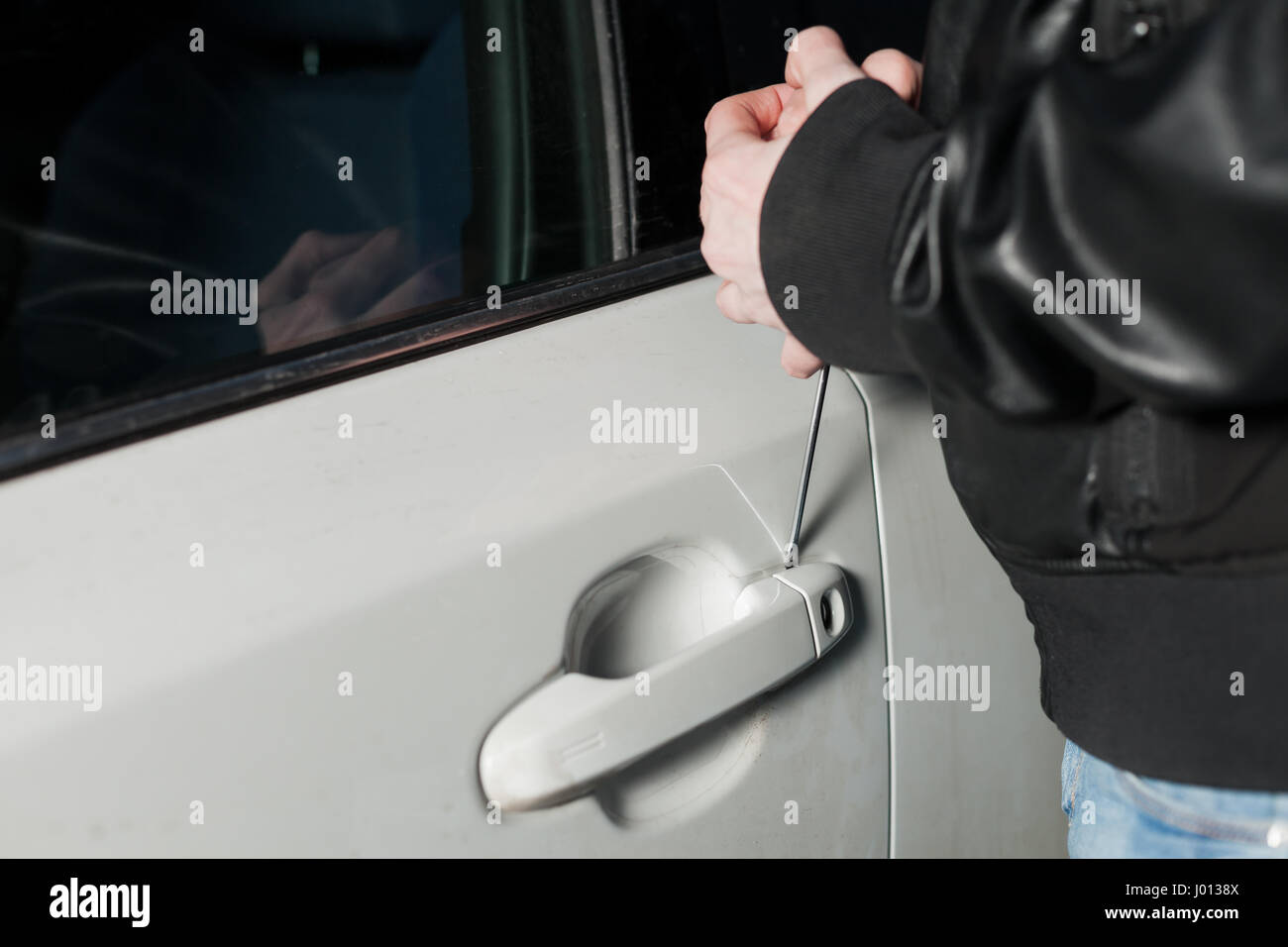 Male Thief Hands Trying To Open Car Door With Screwdriver