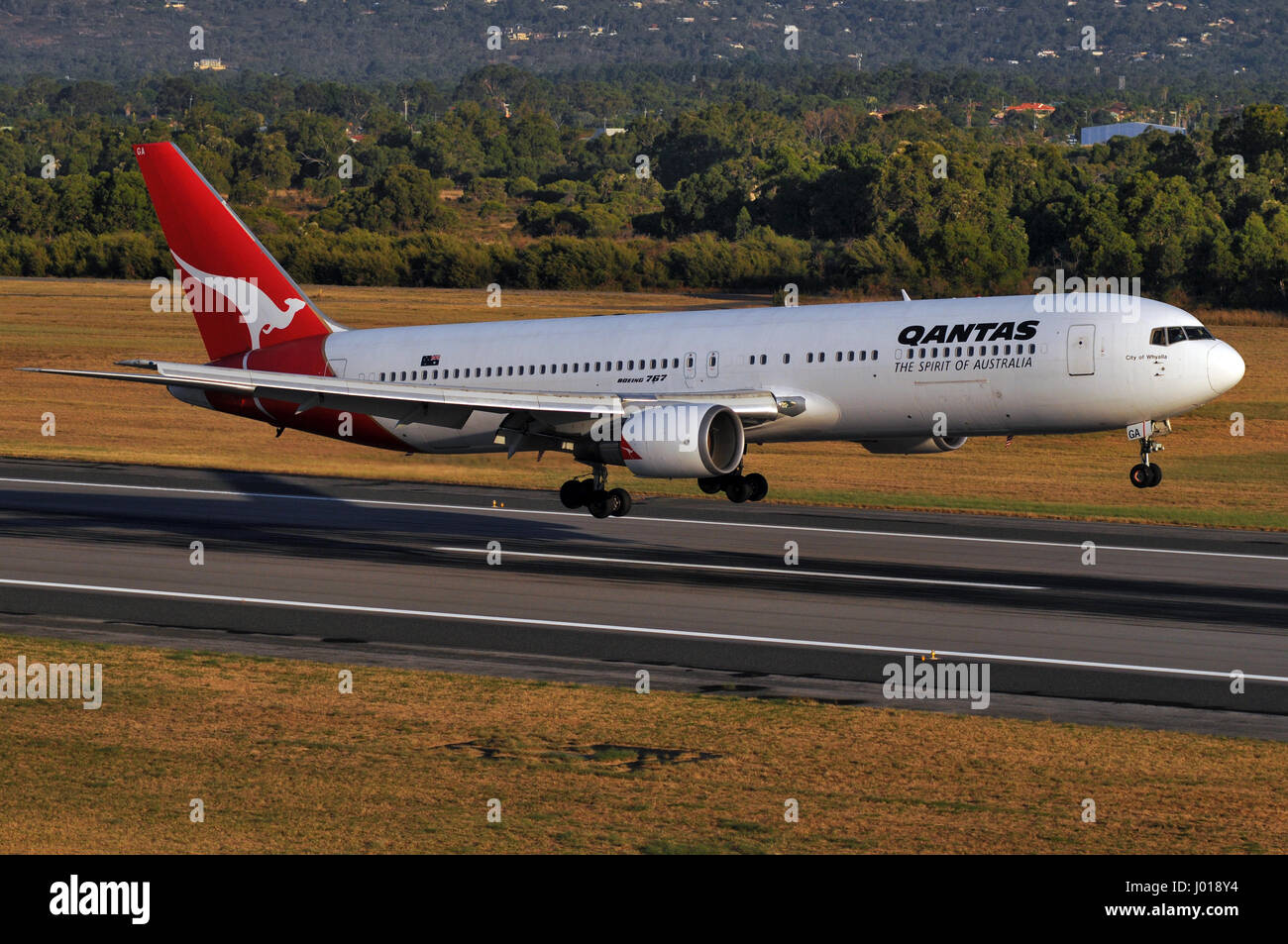 A Qantas Boeing 767 landing at Perth International Airport, in Western Australia. Taken from an R44 helicopter flying alongside. Stock Photo