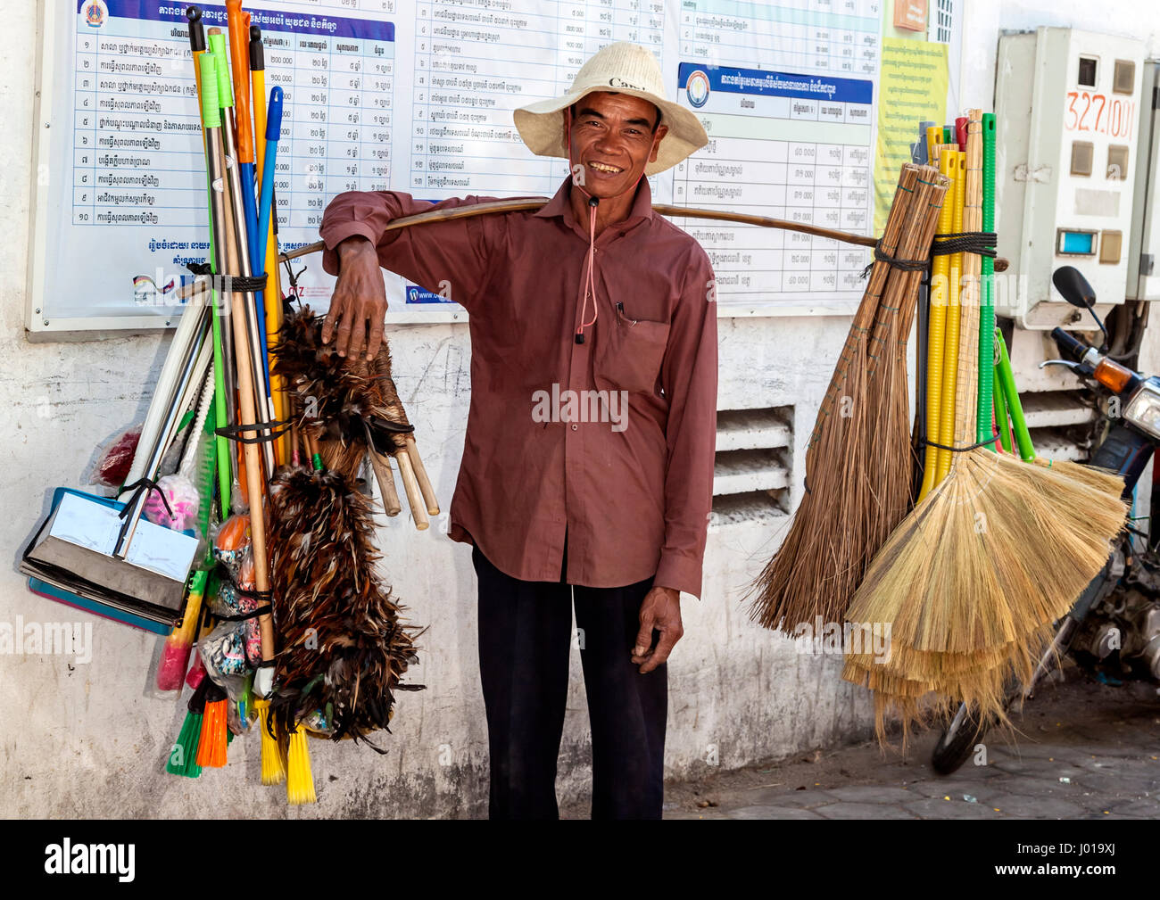 Brush and broom seller carries his goods to maartket Stock Photo