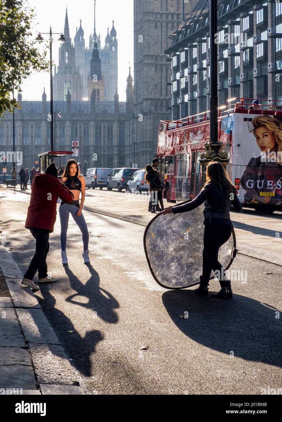 London, England. Model Posing for photographer in a bike lane front of the UK Houses of Parliament, Westminster Palace Government building Stock Photo