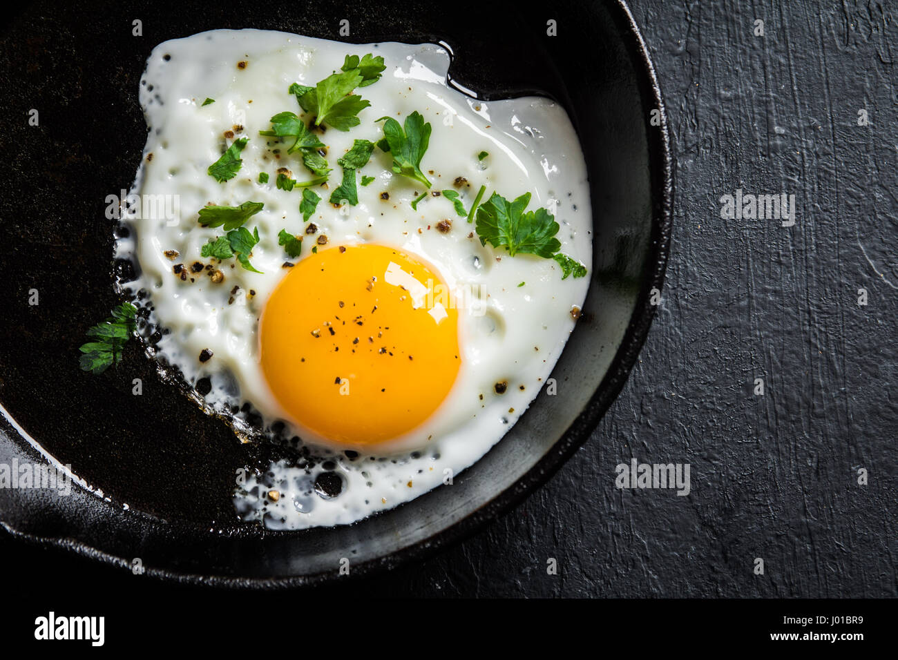 Fried egg. Close up view of the fried egg on a frying pan. Salted and ...