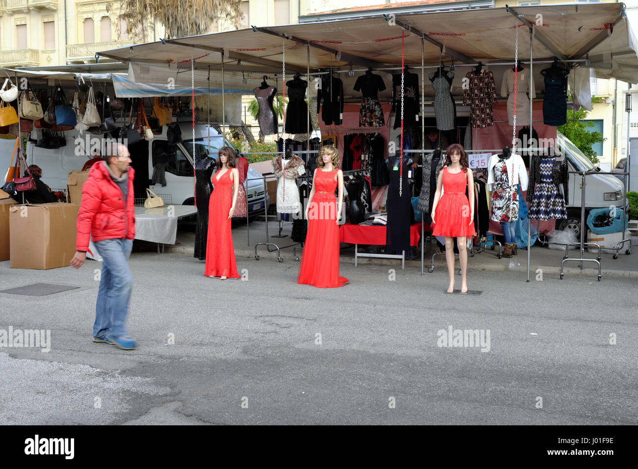 Three mannequins in red dress and man in red down jacket passing by - Viareggio street market, Tuscany, Italy, Europe Stock Photo