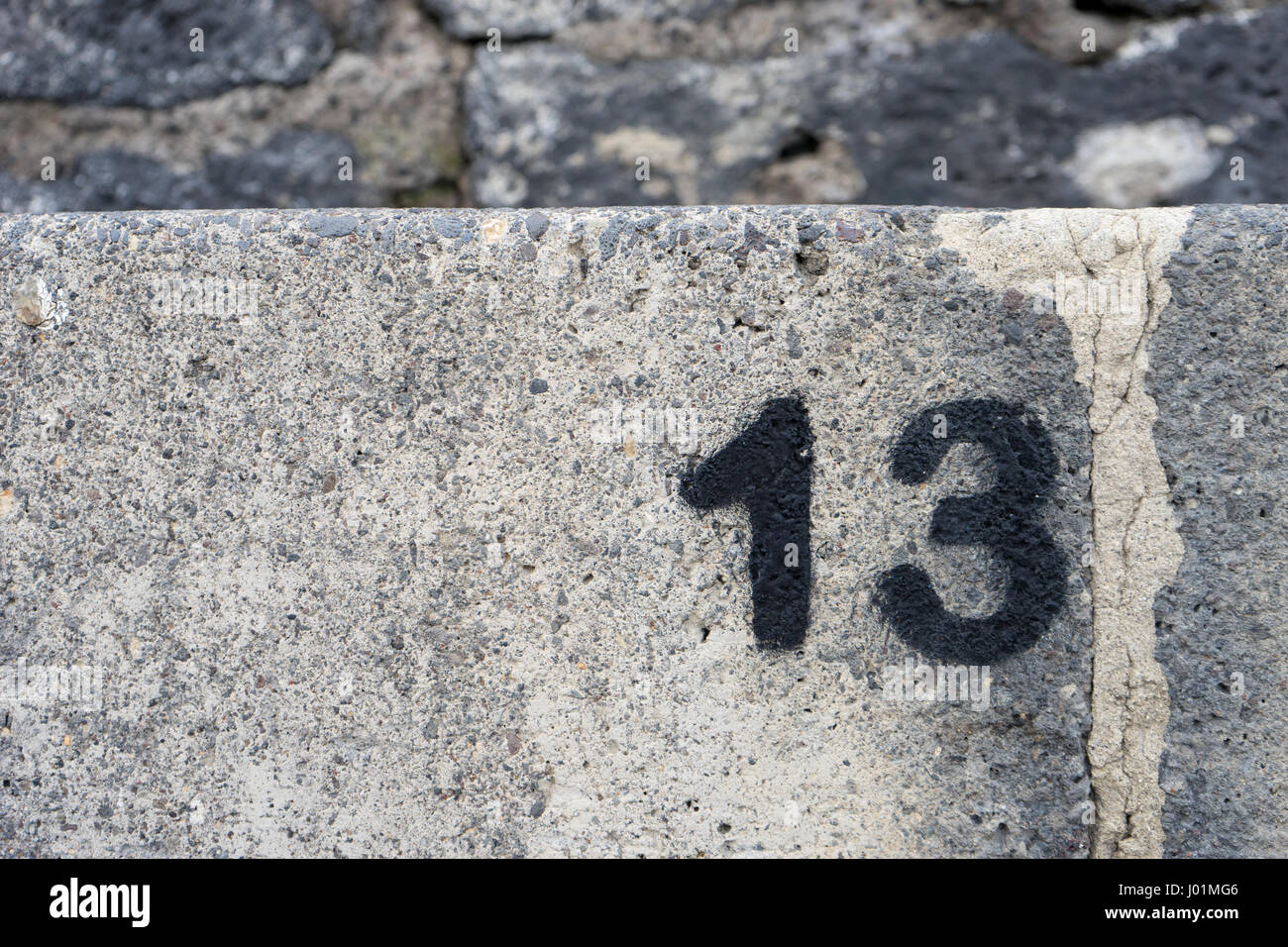 Stone wall with black number thirteen Stock Photo