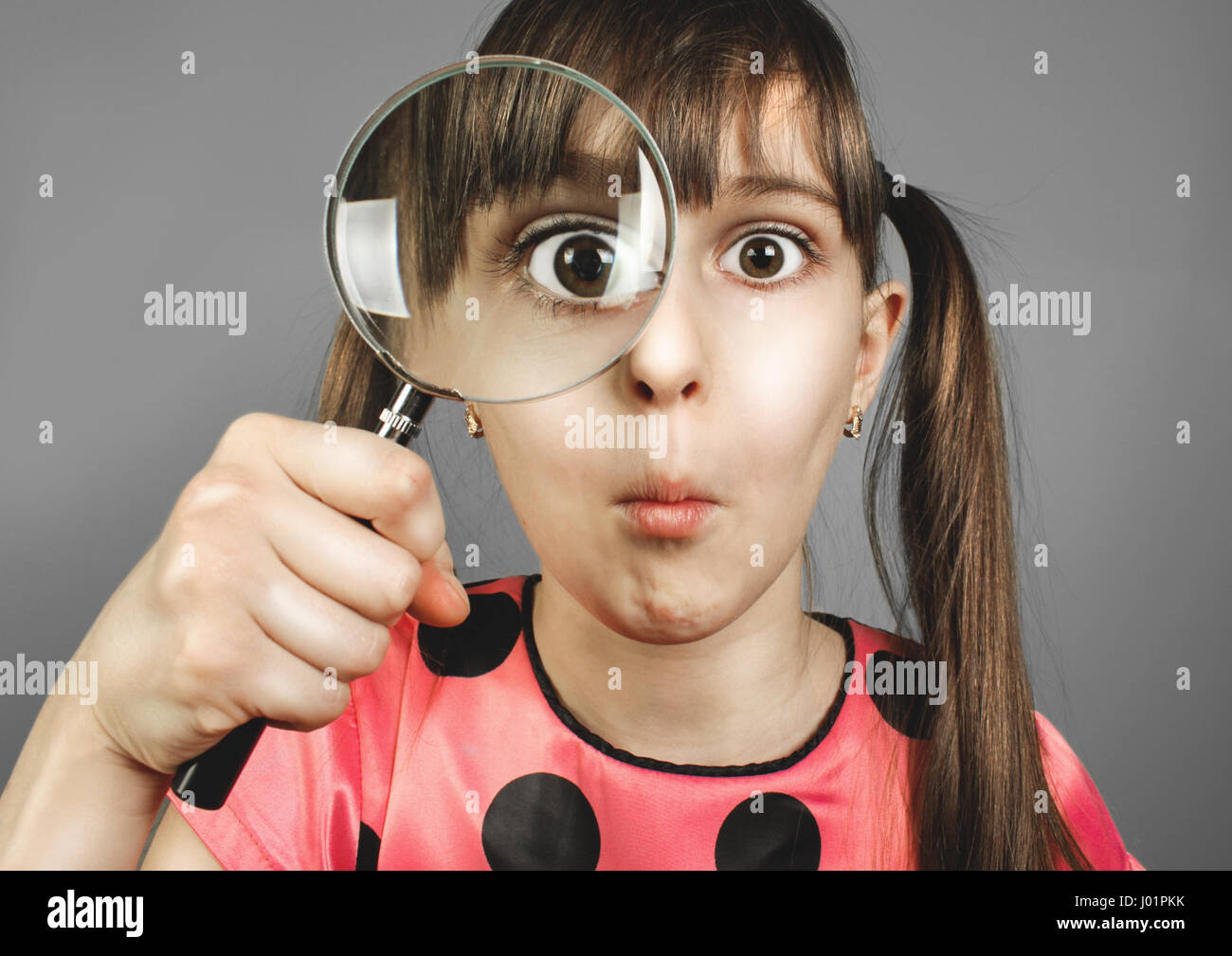 bewilderment child girl looking through magnifying glass Stock Photo
