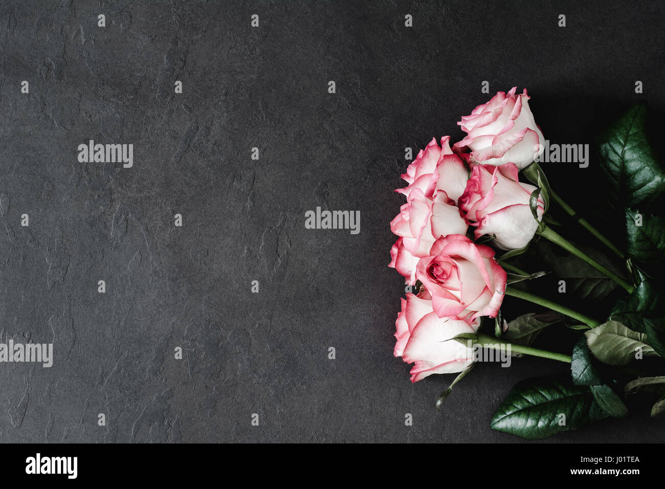 Floral frame: bouquet of pink and white roses on dark stone background with copy space for text. Styled womans day, mothers day floral background Stock Photo