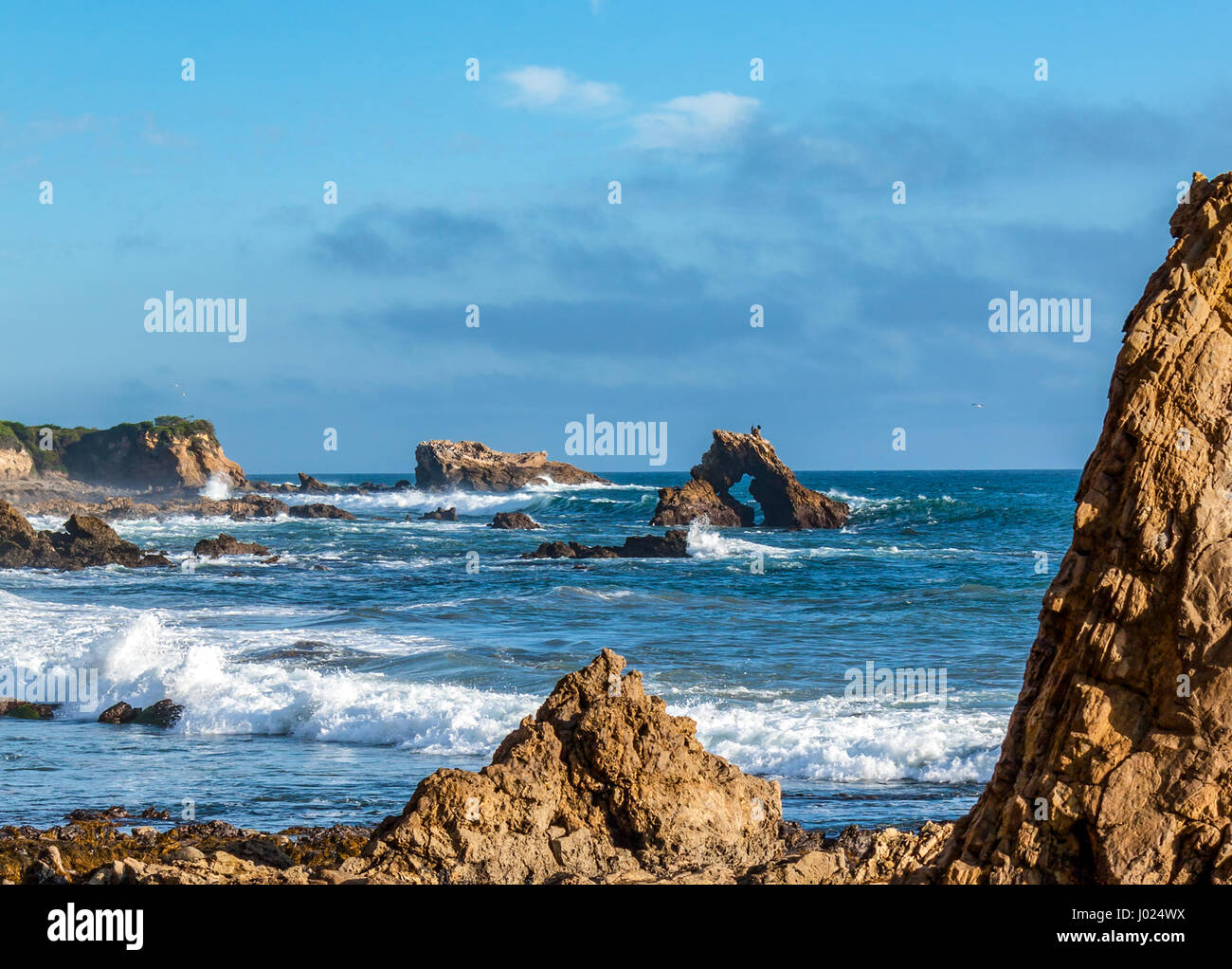 waves crashing on rocky coastline in Newport Beach California Stock Photo