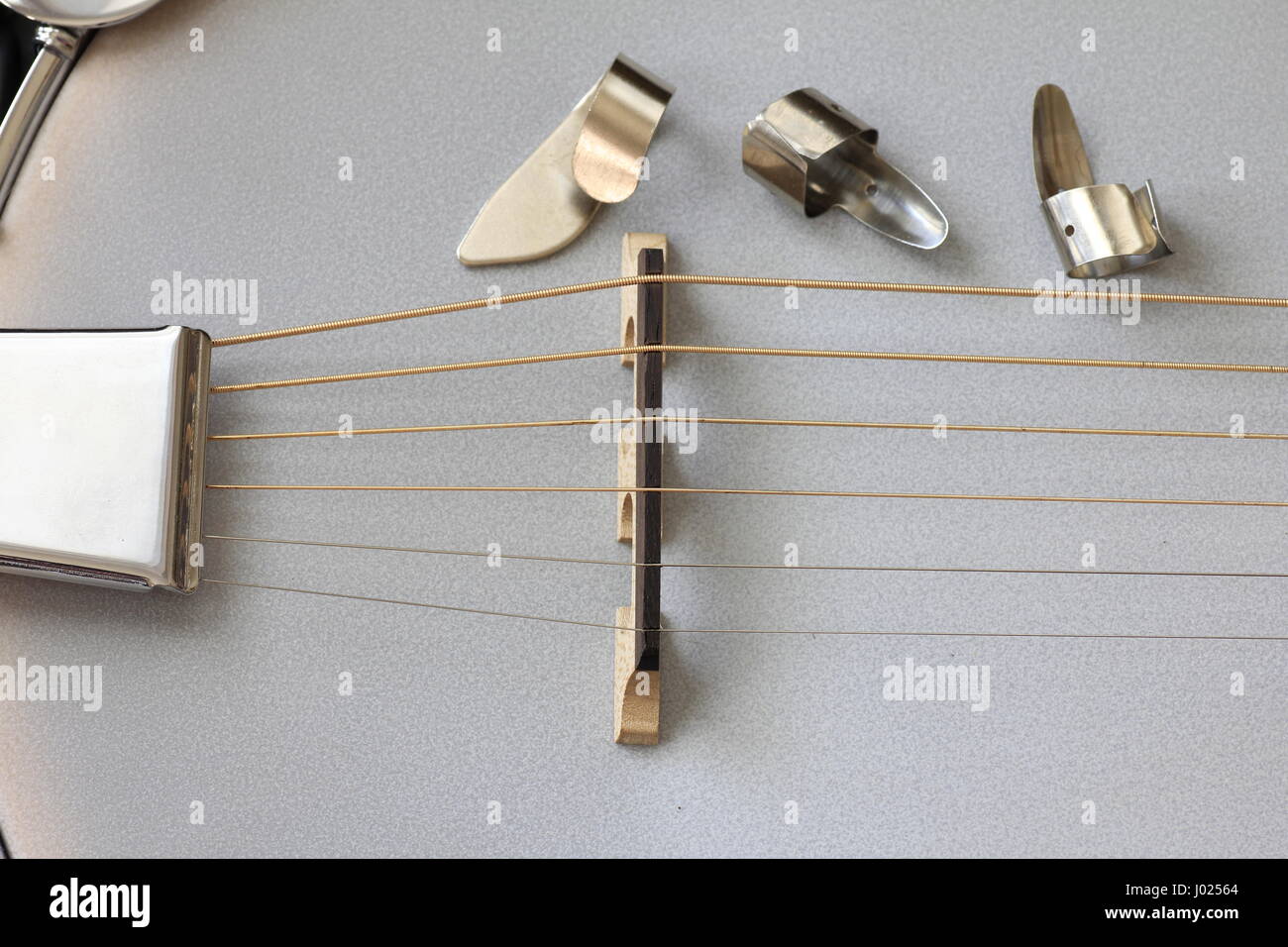 close up of banjo with metal finger picks near strings and bridge Stock