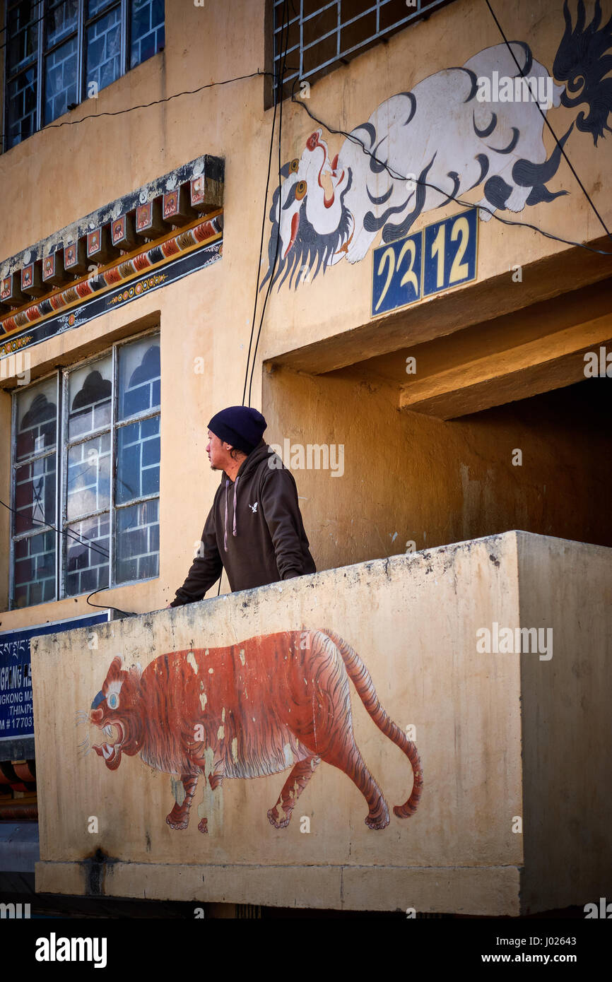 A man looks out from the stairway landing of his apartment in Thimphu Bhutan Stock Photo