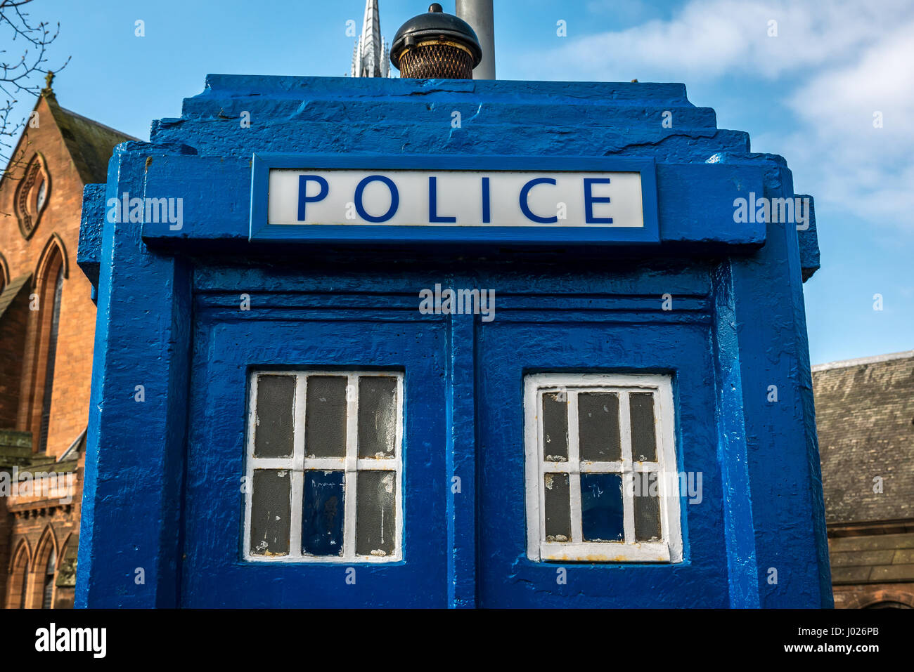 Close up of window panes of old style blue painted police box, like a Tardis, Glasgow, Scotland, UK, with a church in background and blue sky Stock Photo