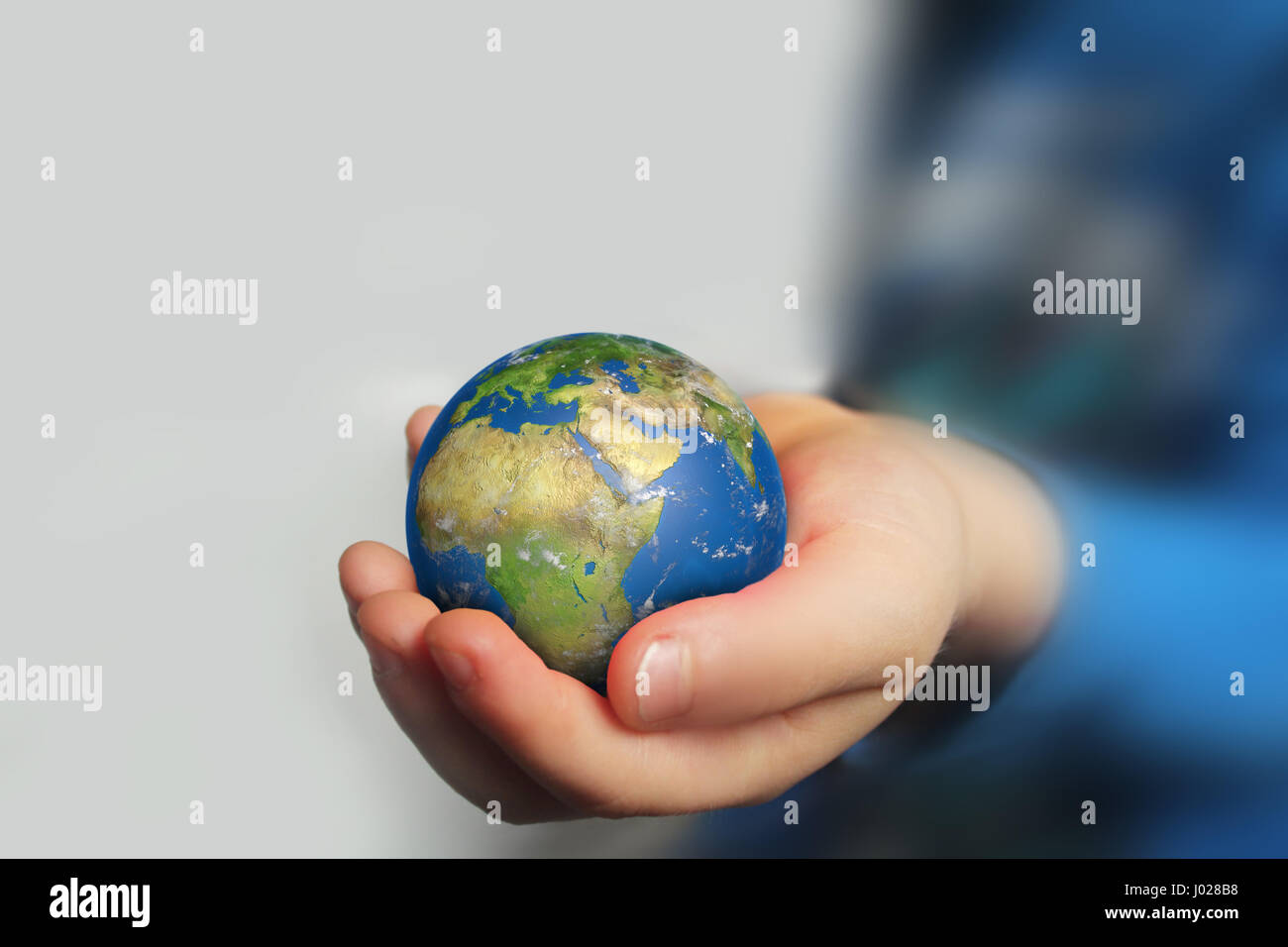 Child's hand holding globe on blured background Stock Photo