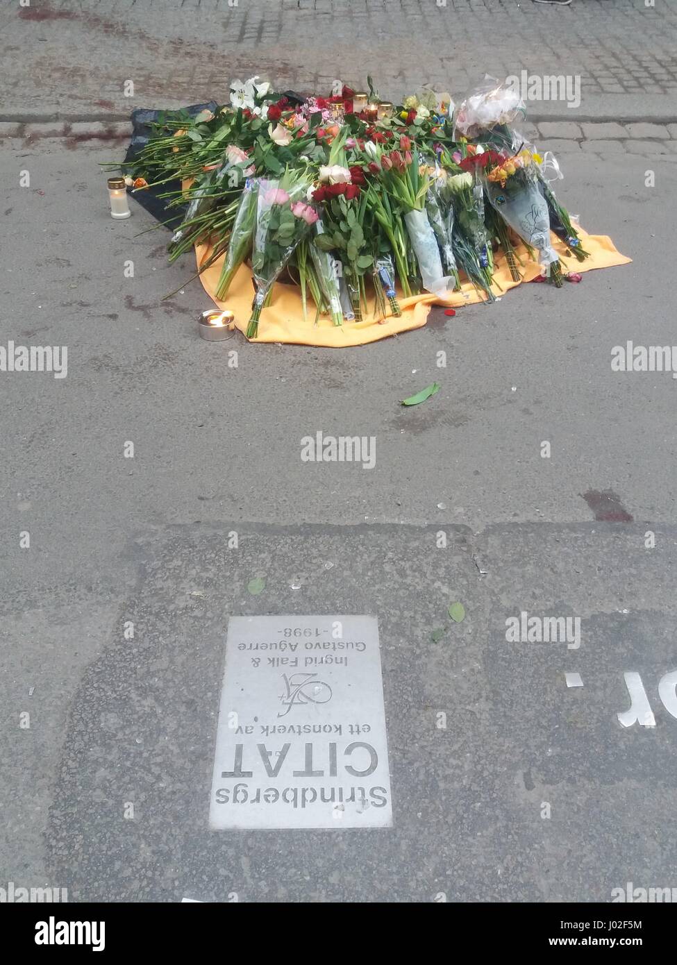 A stack of accumulated flower bouquets laid on the ground of the the street where the attacker's truck crashed into a department store. Central Stockholm Stock Photo