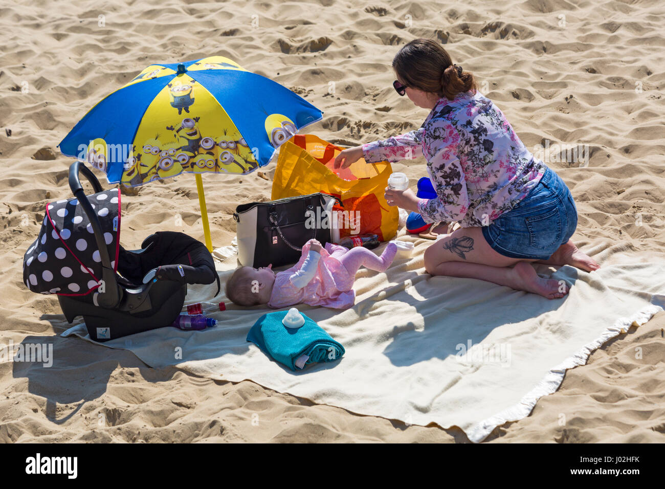 Bournemouth, Dorset, UK. 9th Apr, 2017. UK weather: lovely warm sunny day as visitors head to the seaside to make the most of the sunshine at Bournemouth beaches. Woman preparing food drink for baby lying on blanket at the beach.  Credit: Carolyn Jenkins/Alamy Live News Stock Photo
