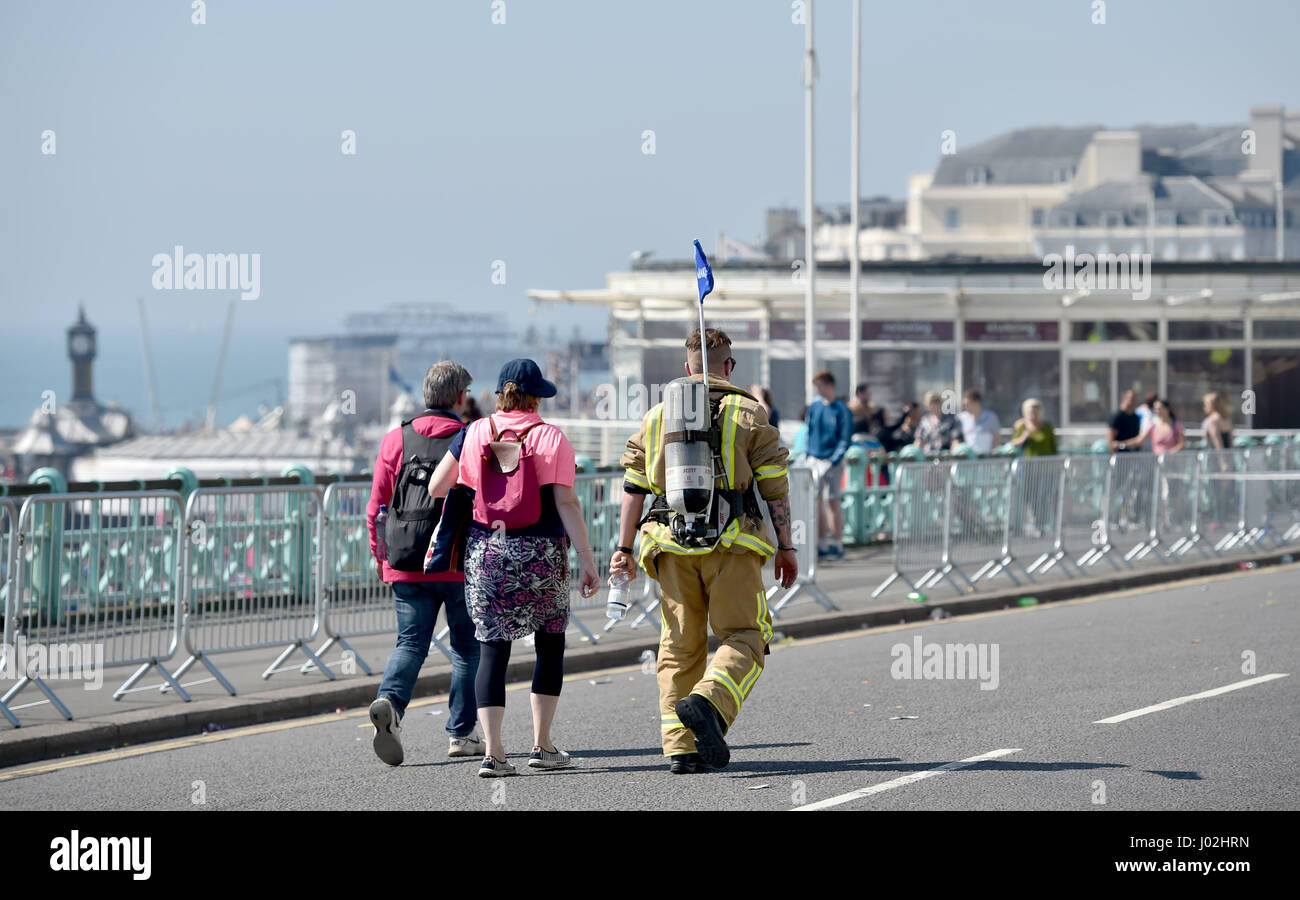 Brighton UK 9th April 2017 - A fire officer in full kit  finds it hot work on the seafront in the Brighton Marathon today on a beautiful sunny warm day with temperatures reaching as high as 24 degrees celsius in some parts of the country Photograph taken by Simon Dack Stock Photo