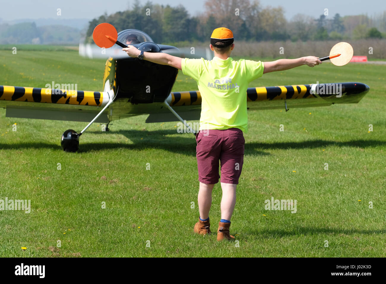 Shobdon airfield, Herefordshire, UK. April, 2017. General aviation airfield ground marshaller directs a taxying Vans RV-8 aircraft. Credit: Steven May/Alamy Live News Stock Photo