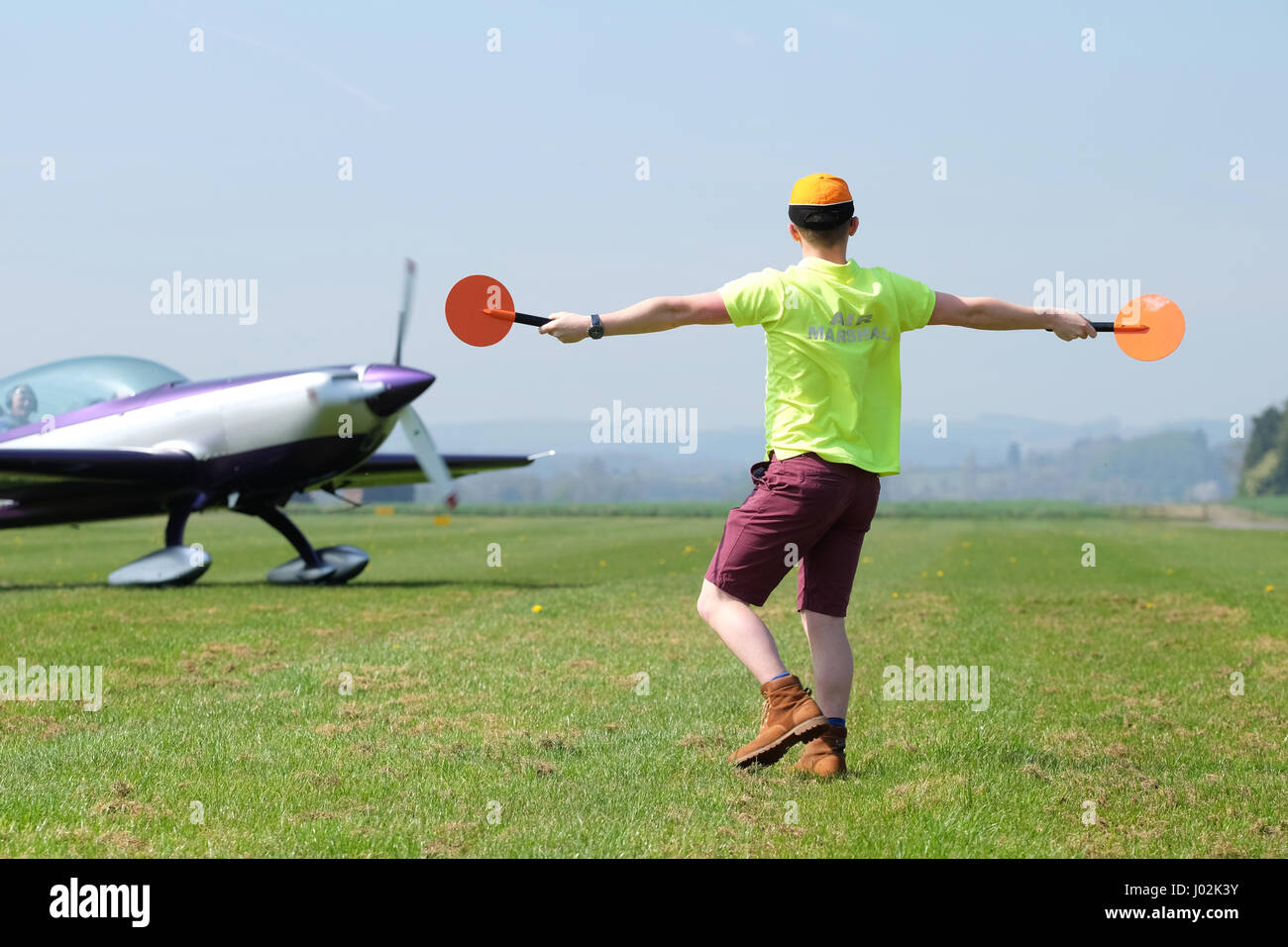 Shobdon airfield, Herefordshire, UK. April, 2017. General aviation airfield ground marshaller directs a taxying Extra EA300 aircraft. Credit: Steven May/Alamy Live News Stock Photo
