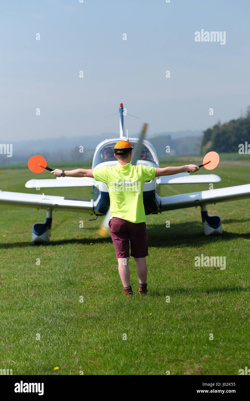 Shobdon airfield, Herefordshire, UK. April, 2017. General aviation airfield ground marshaller directs a taxying Piper Pa-28 Cherokee aircraft. Credit: Steven May/Alamy Live News Stock Photo