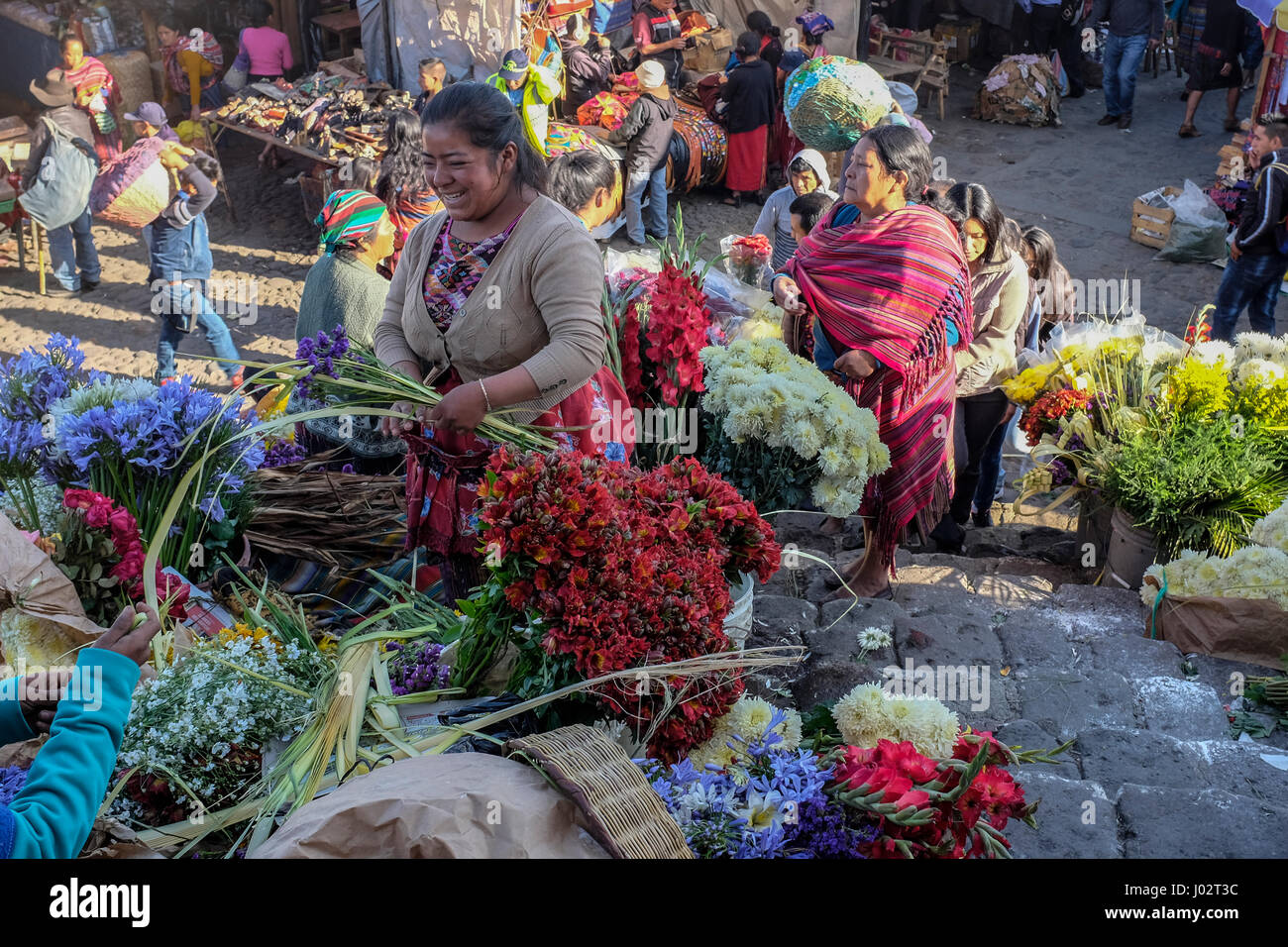 A mayan woman sells flowers in front of the church at the Sunday market in Chichicastenango, Guatemala. Stock Photo