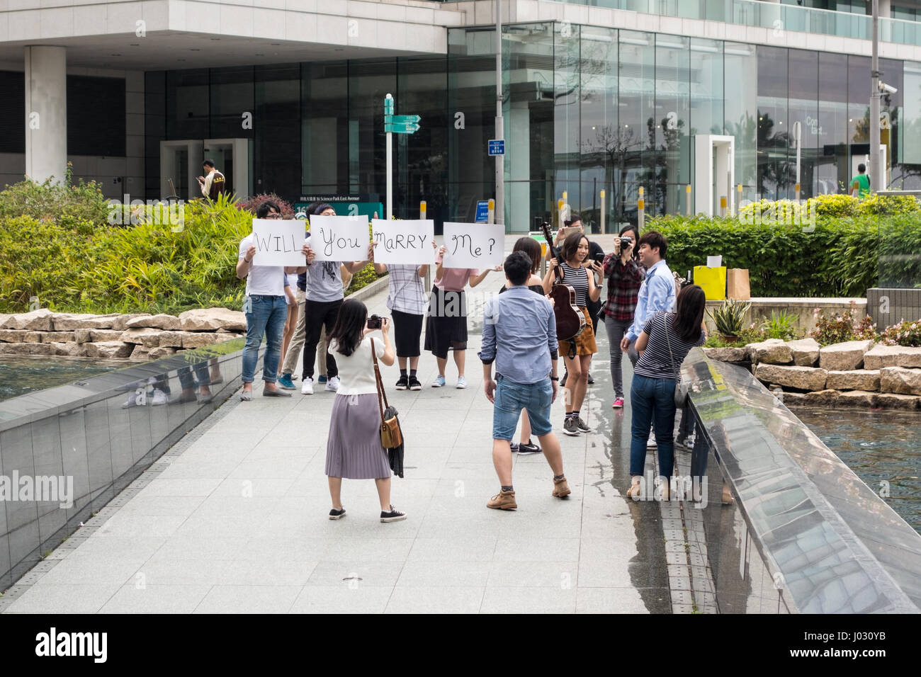 Marriage proposal with friends holding up 'Will You Marry Me' signs in Hong Kong SAR Stock Photo