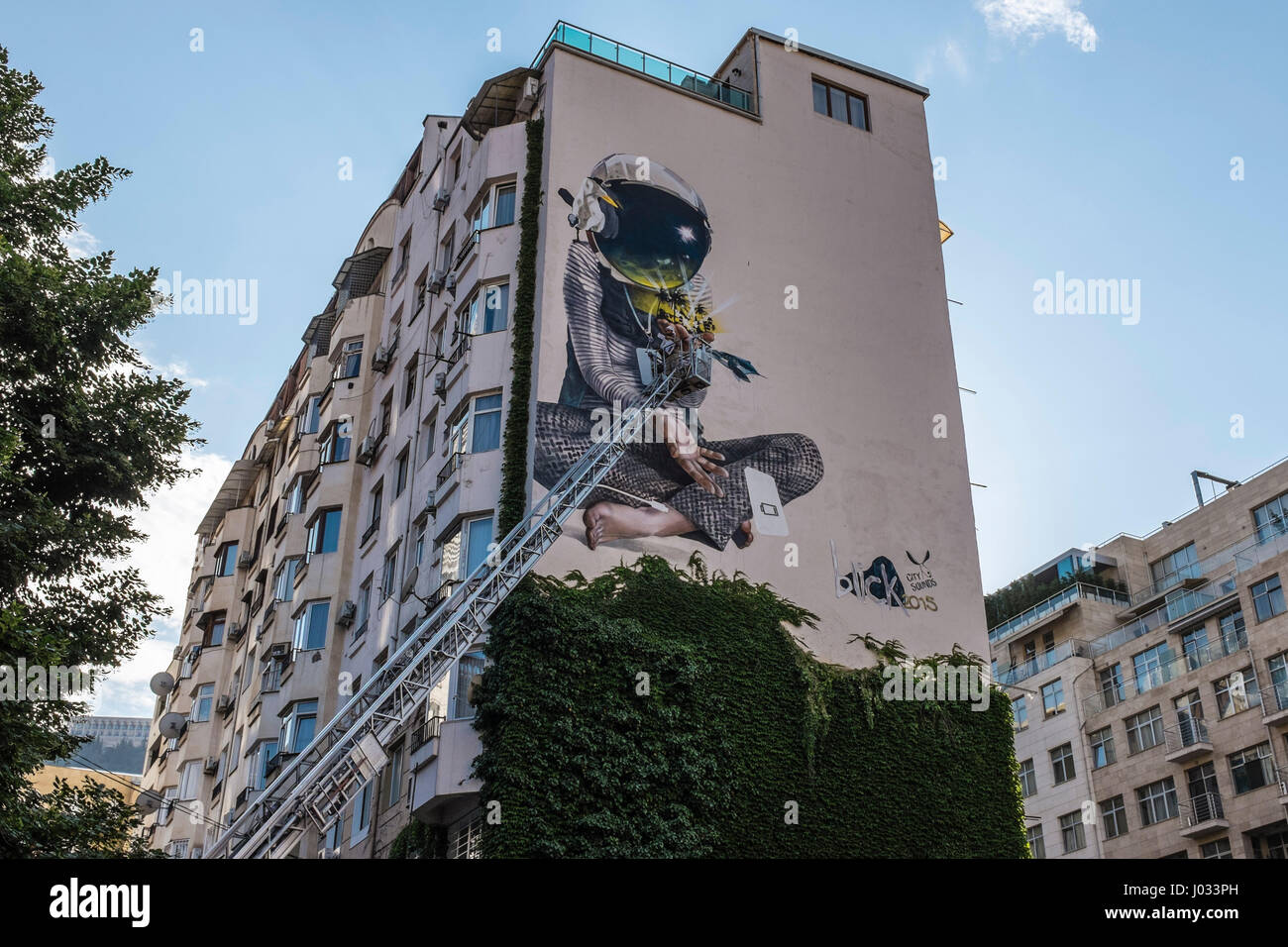 Street art graffiti being painted on apartment building in Tbilisi, Georgia, Eastern Europe Stock Photo