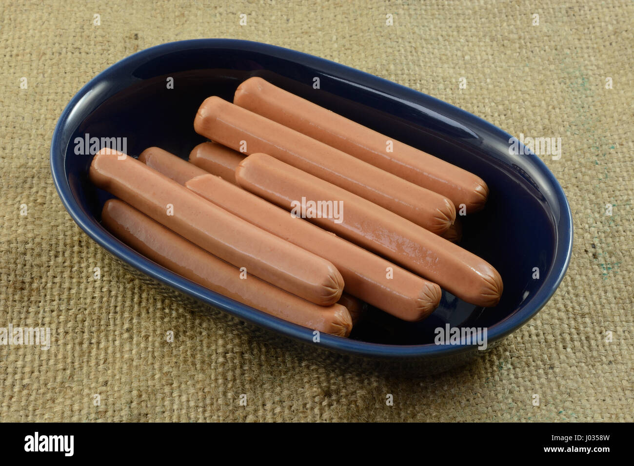 Raw uncooked turkey hot dog frankfurters in blue bowl for cooking
