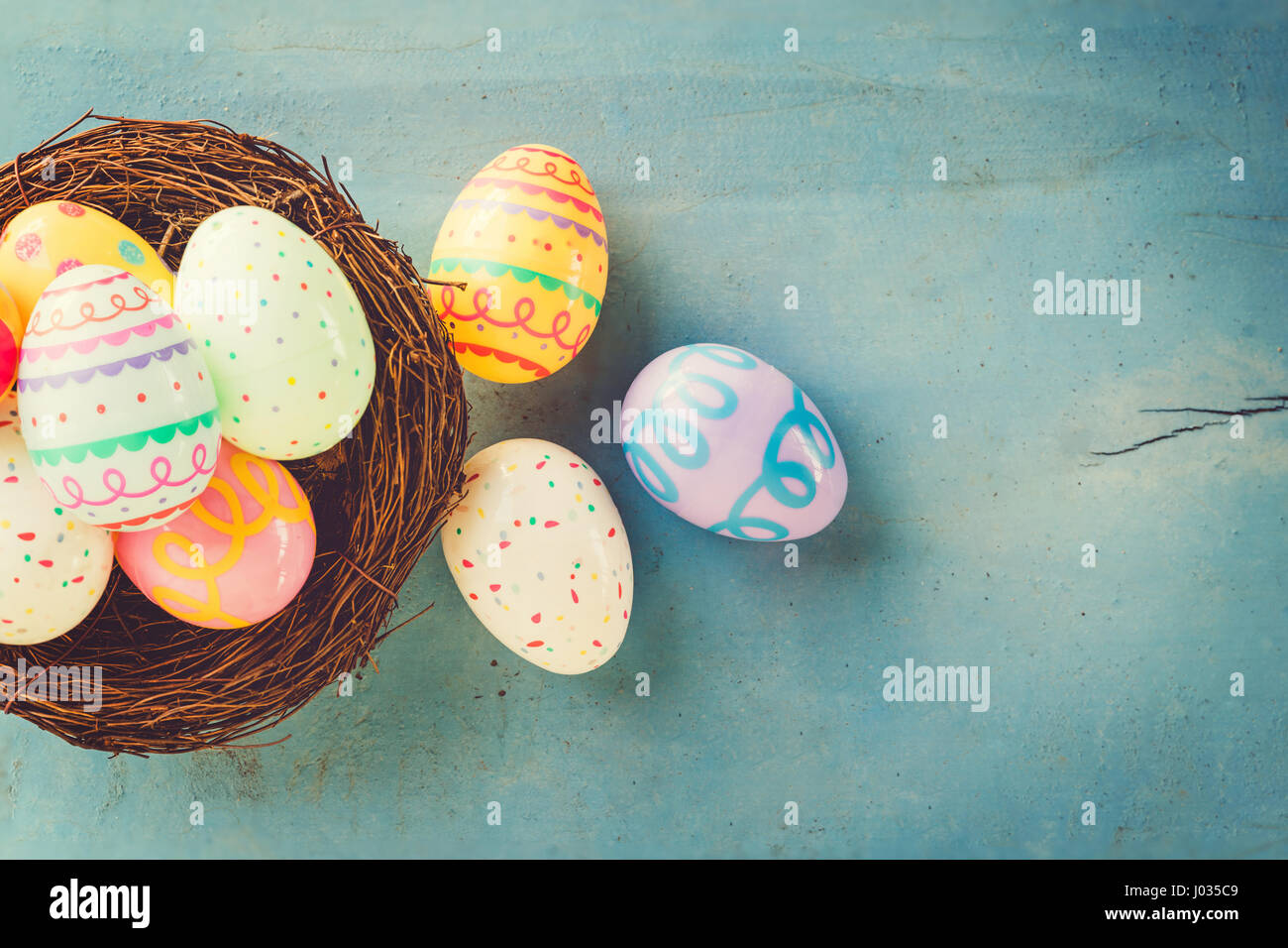 Colorful easter eggs in nest on blue wood background with copy space ...