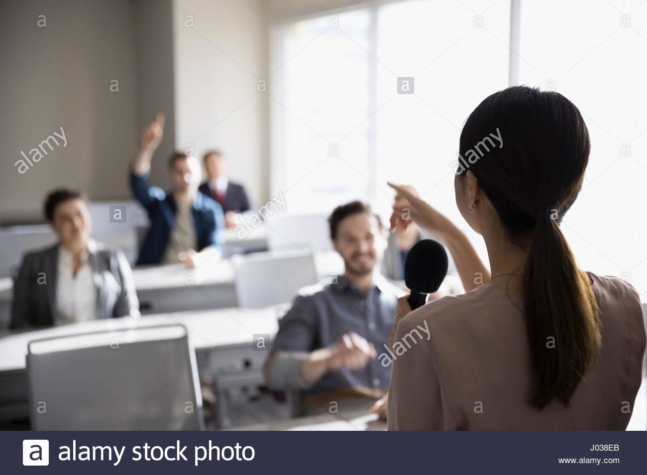 Businesswoman with microphone answering audience questions in office classroom Stock Photo