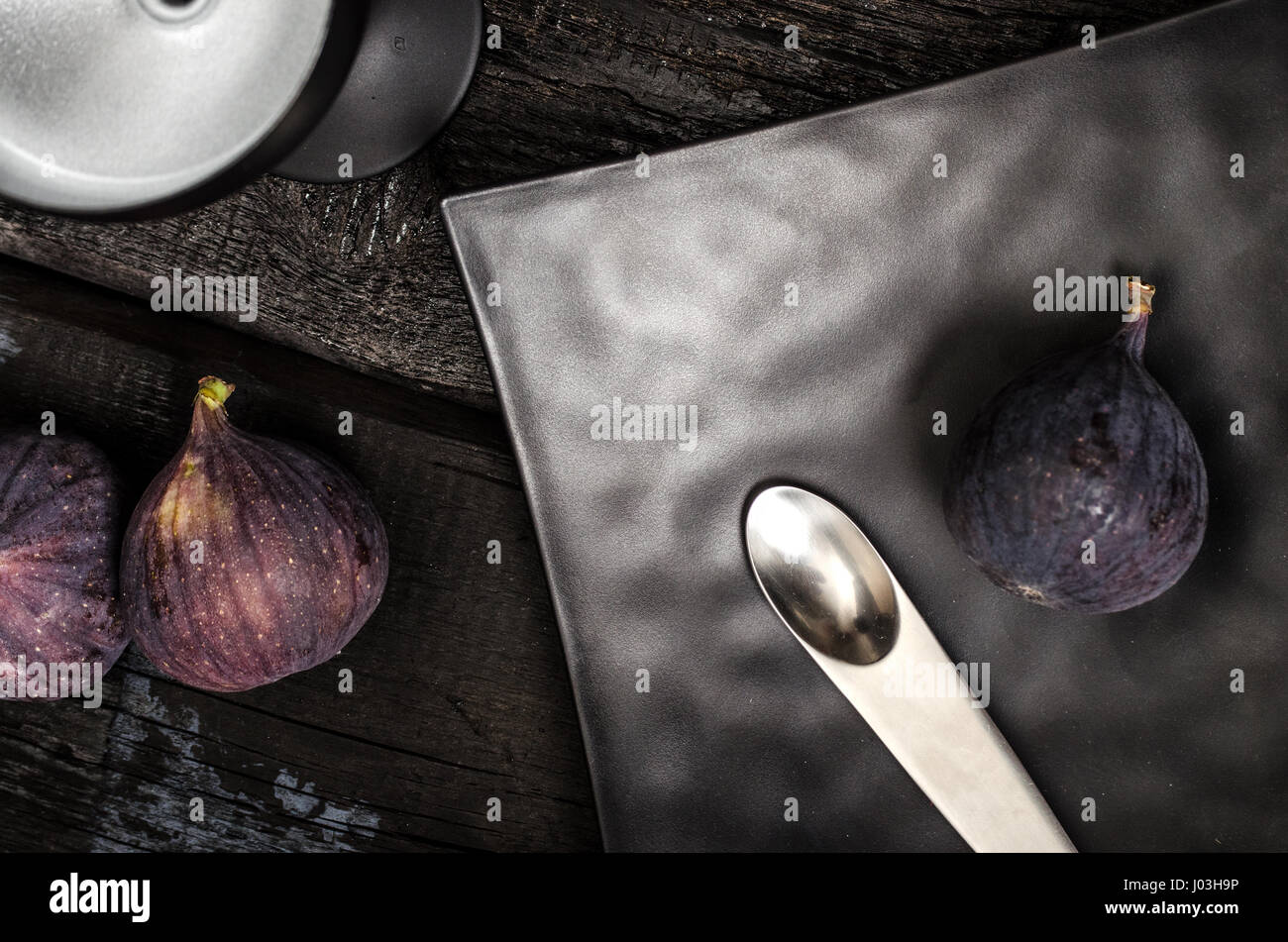 Unusual spoon, black plate and cocktail glass. Figs as decoration. Still life. Stock Photo