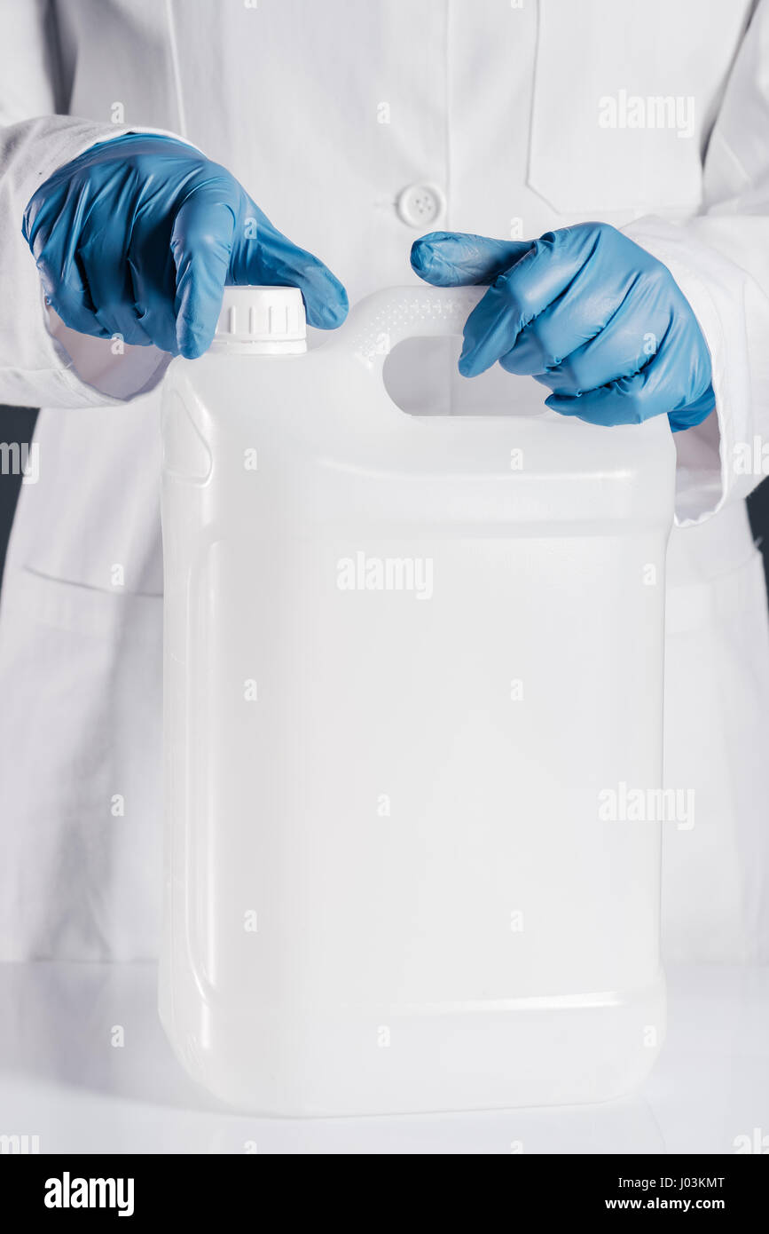 Chemical scientist opening white unlabeled plastic tank canister with chemicals on laboratory table Stock Photo