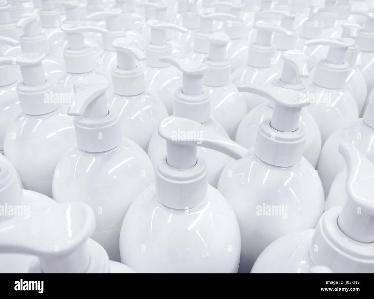 White unlabeled liquid soap bottles in supermarket, repeating pattern of large group of plastic containers for hygiene product Stock Photo