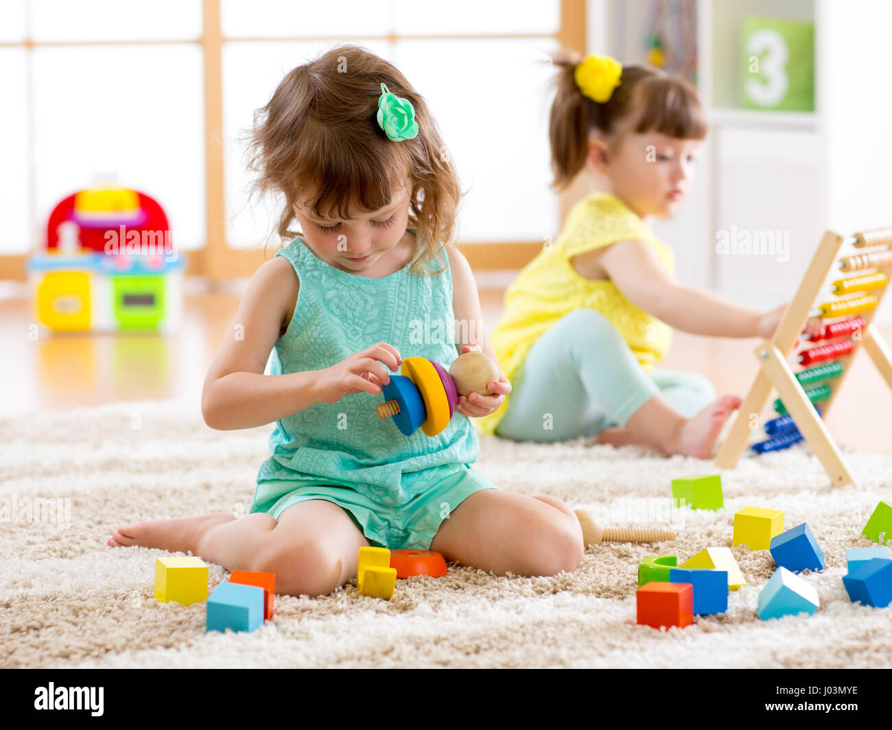Children toddler and preschooler girls play logical toy learning shapes