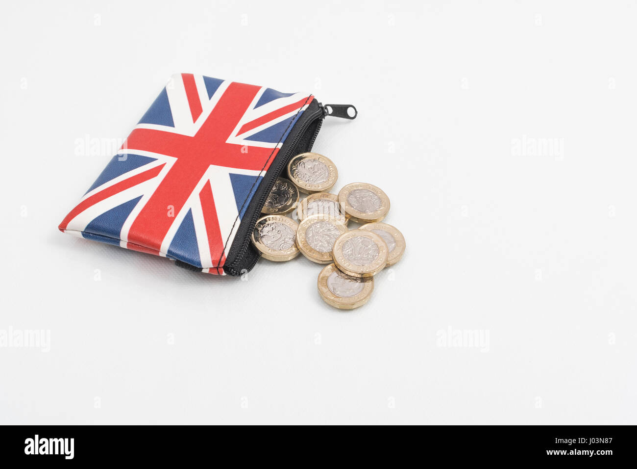 New UK £1 / One pound coins with a Union Jack coin purse on a plain background. Metaphor for 'rising cost of living', affordability, spendthrift 30s. Stock Photo
