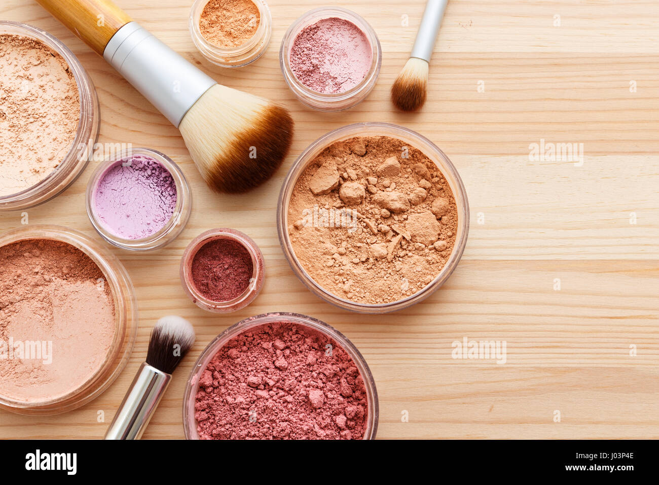 Makeup powder with foundation eye shadow and brushes on wood background Stock Photo