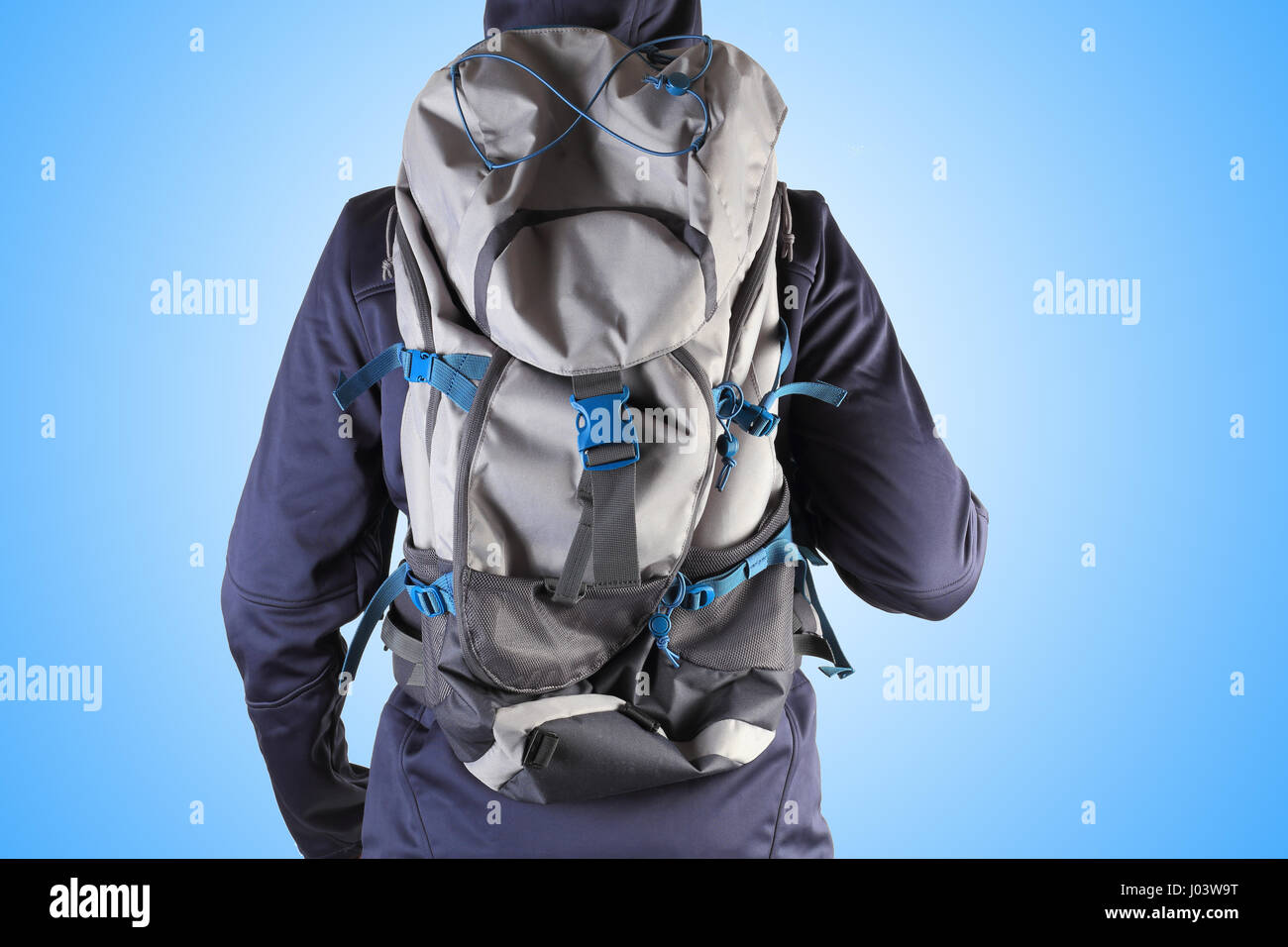 Hiker with backpack on blue background. New backpack on man back close-up. Excellent travel background. Stock Photo