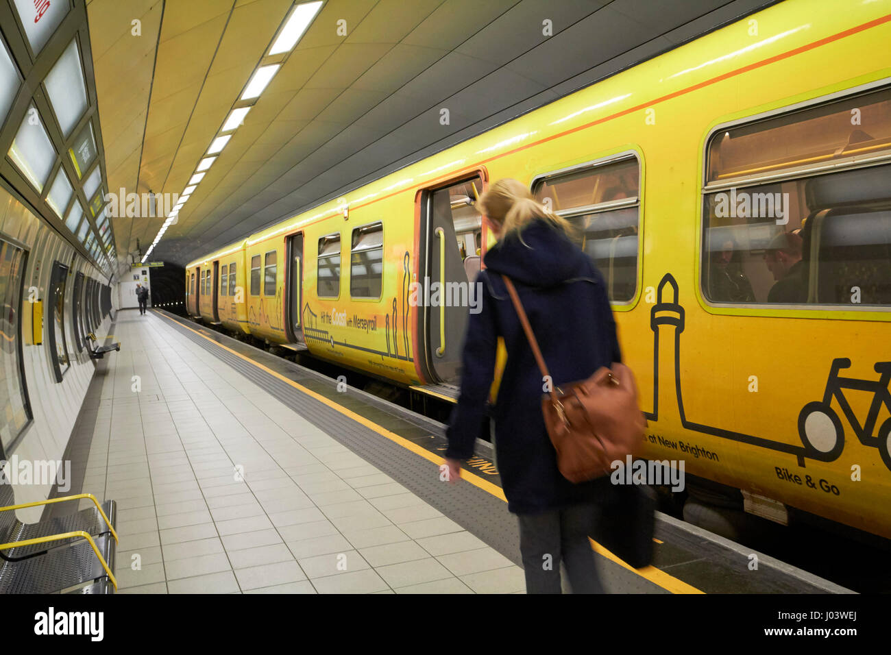 lone woman passenger boarding merseyrail train in james street underground train station Liverpool UK Stock Photo