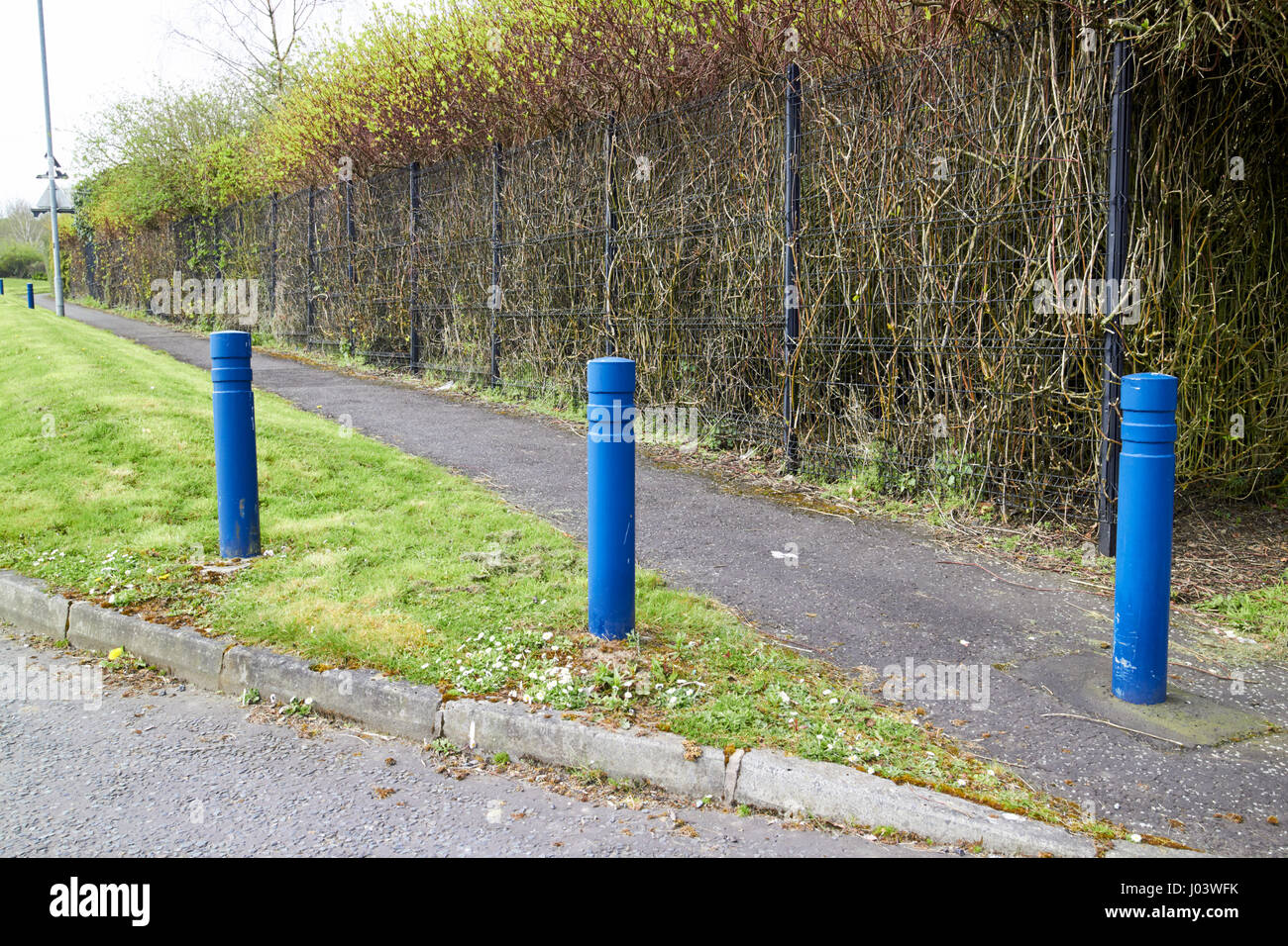security bollards and grass earth berm protecting footpath in secure commercial area Newtownabbey UK these installations were common designs in the tr Stock Photo