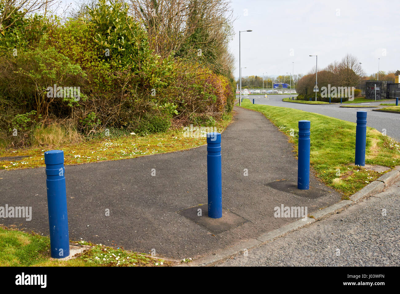 security bollards and grass earth berm protecting footpath in secure commercial area Newtownabbey UK these installations were common designs in the tr Stock Photo