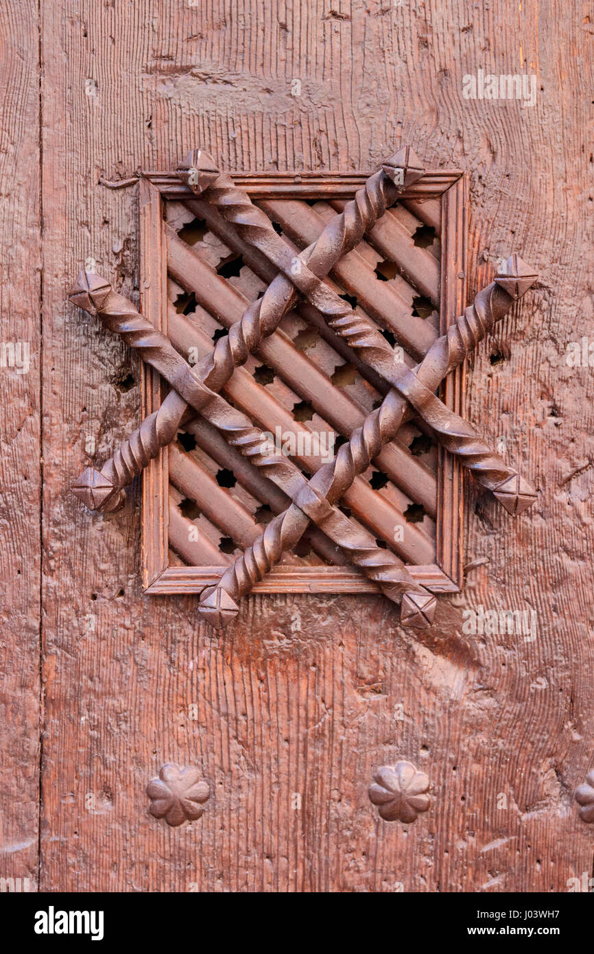 Ornamented spyhole in an old wooden door. Albarracin, Teurel, Spain. Tone filtered to achieve nostalgic effect. Stock Photo