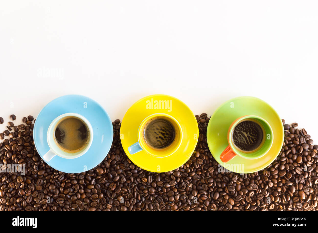 Colorful coffee cups lined up on coffee beans isolated on white background for web banner Stock