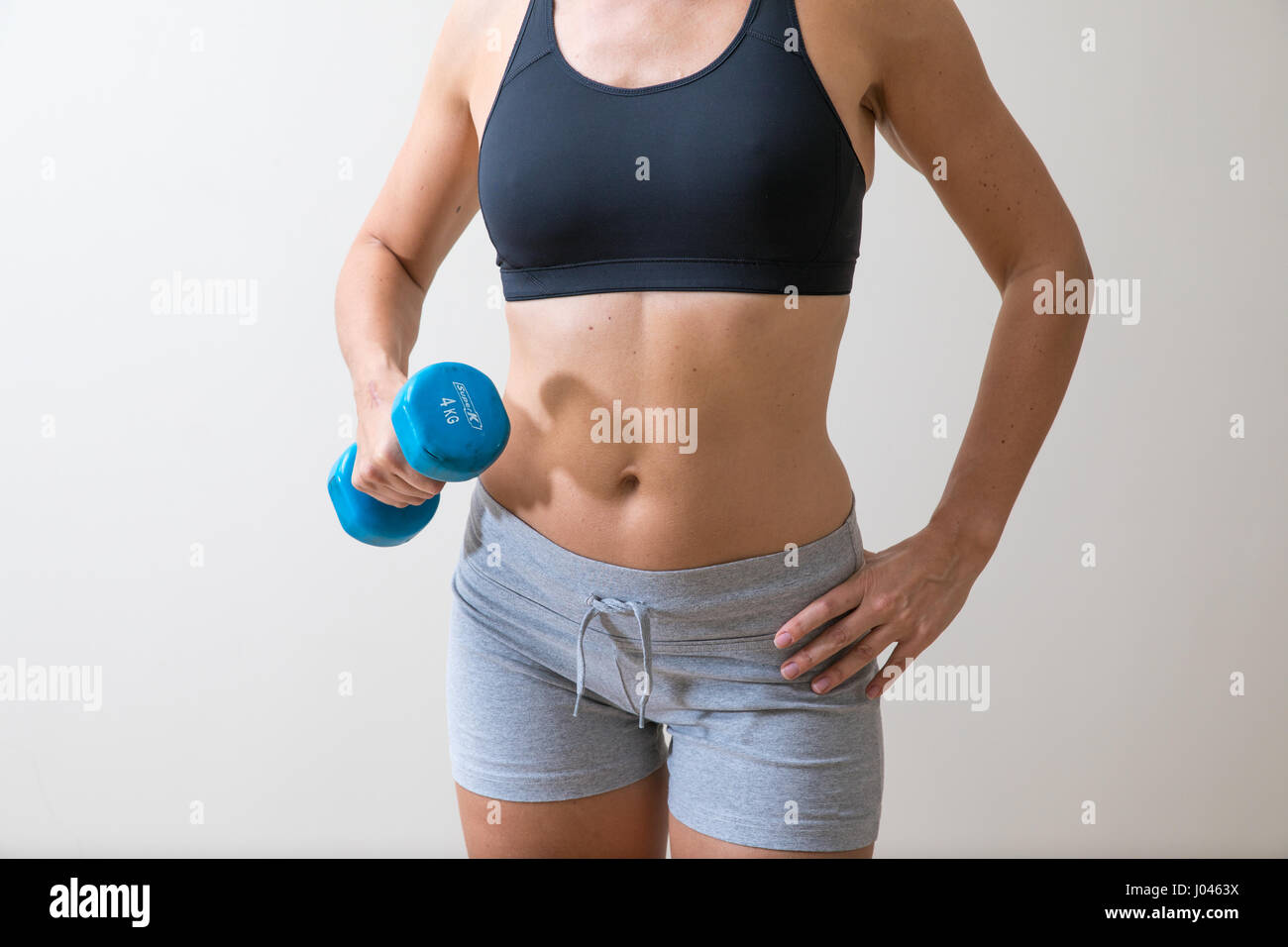 Middle aged woman in gym gear with a blue dumb bell. Stock Photo