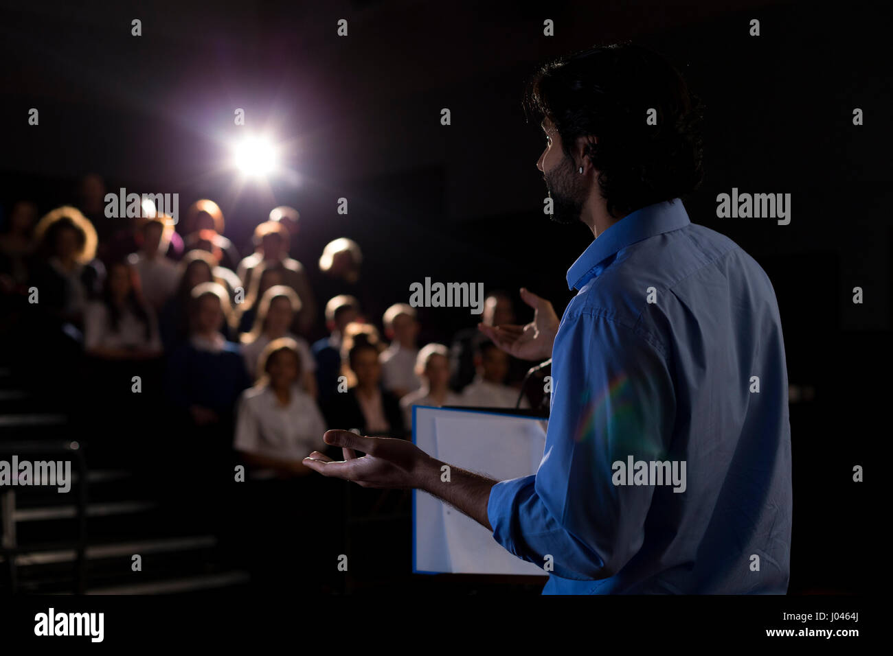 Male teacher giving a speech in a lecture hall to students and teachers. Stock Photo