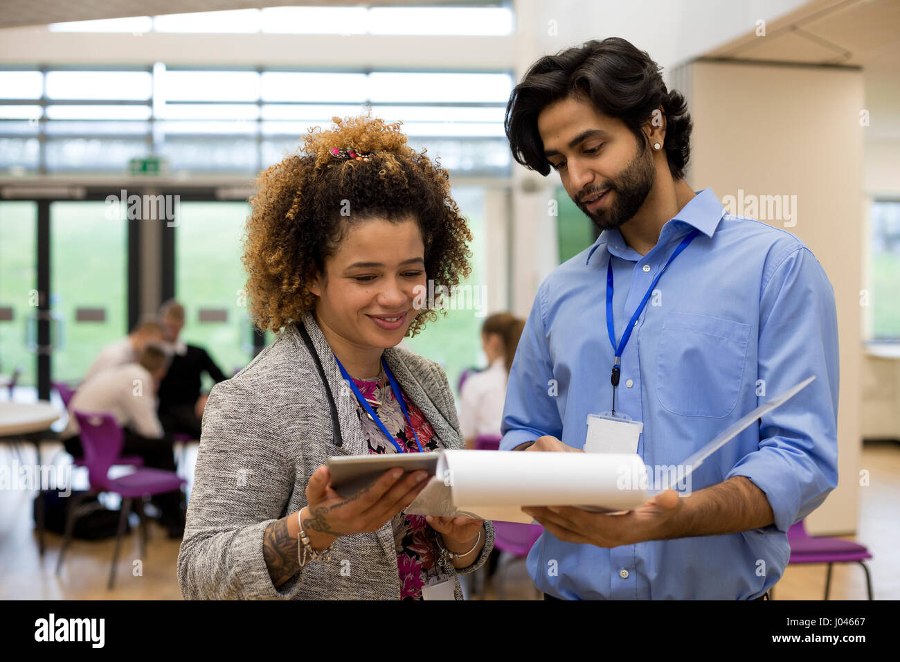 Two teachers are holding some paperwork in front of them and are discussing it together. Stock Photo