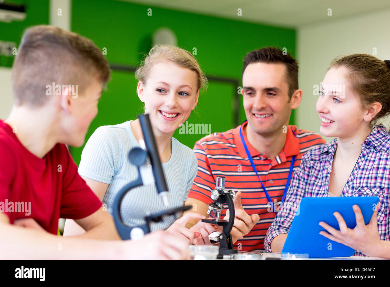 Teacher is supervising his students as they experiment with microscopes Stock Photo