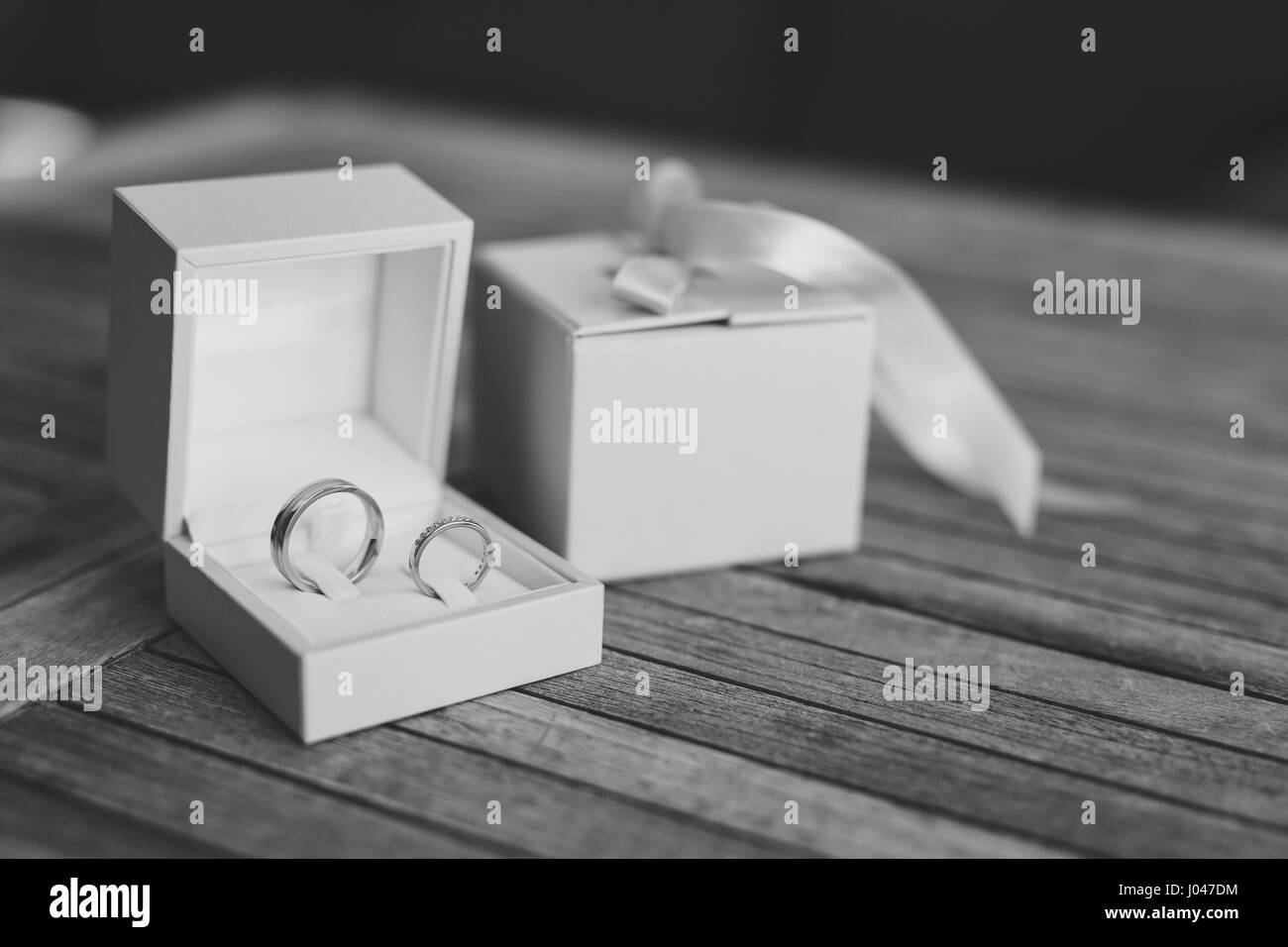 Wedding rings on a light wooden texture in a blue box. Wedding jewelry. Black and white