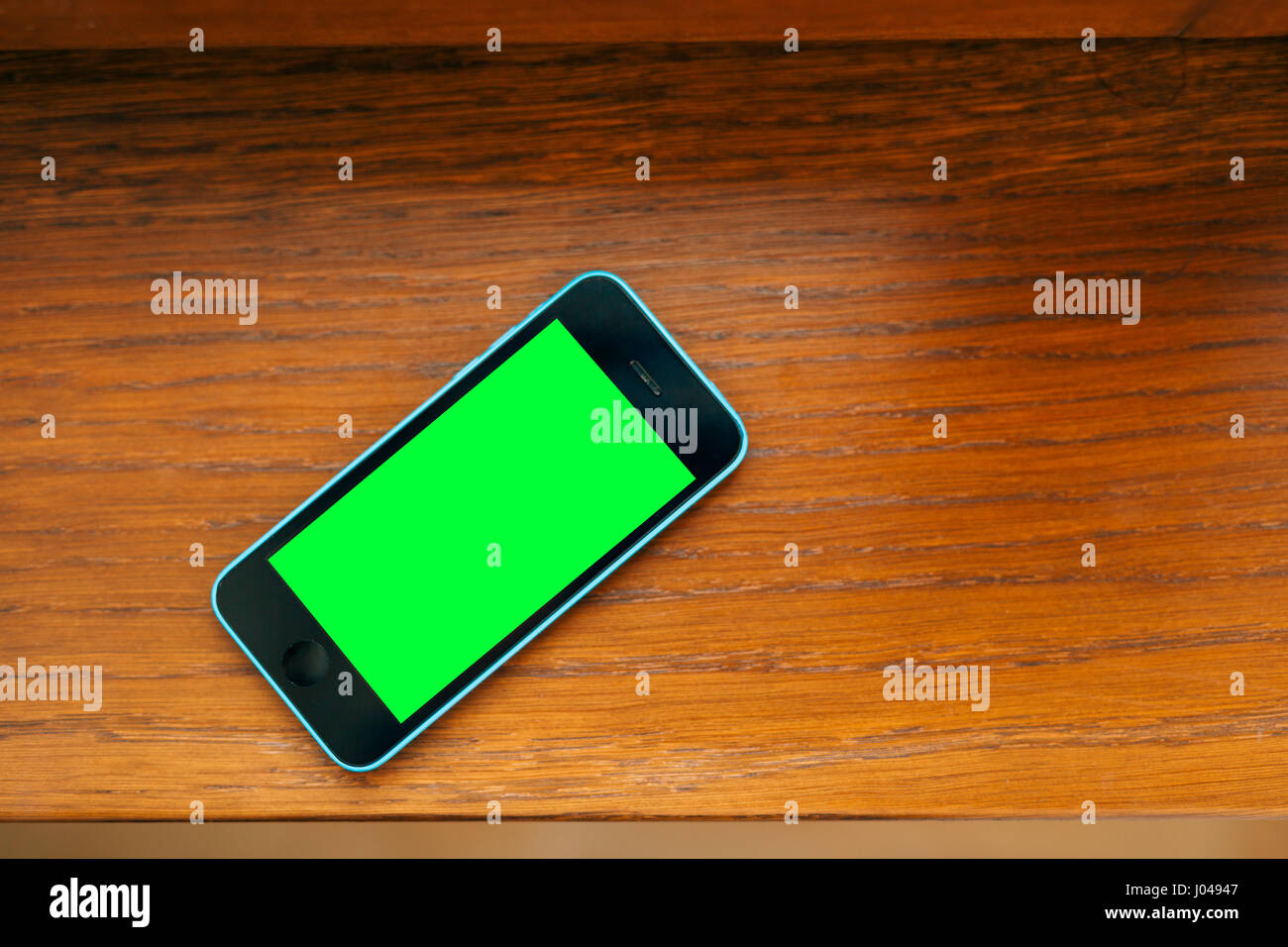 Black and blue phone on the table with green screen Stock Photo Alamy
