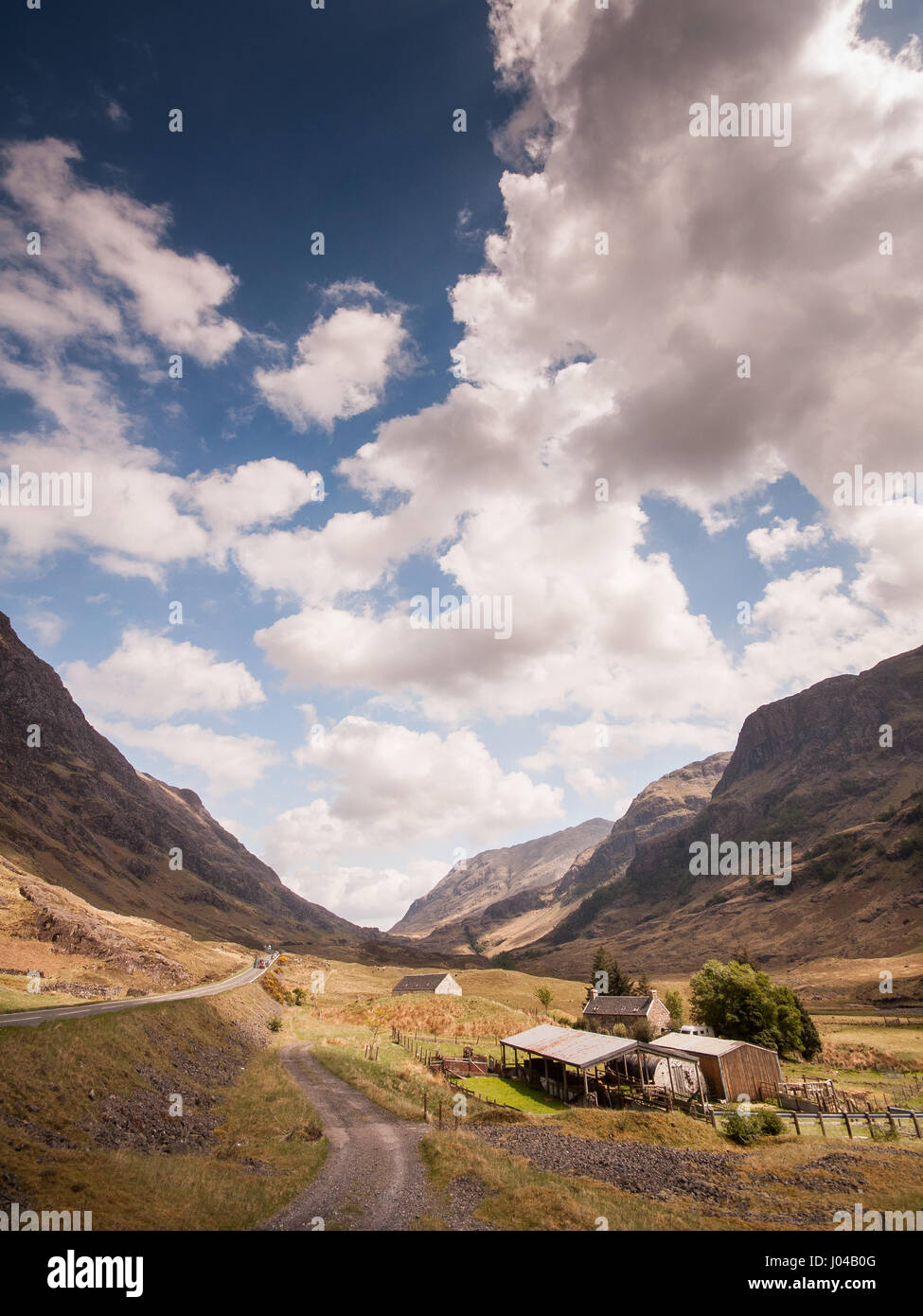 A farmhouse and farmland in the valley floor of Glen Coe, under the mountains of the Highlands of Scotland. Stock Photo
